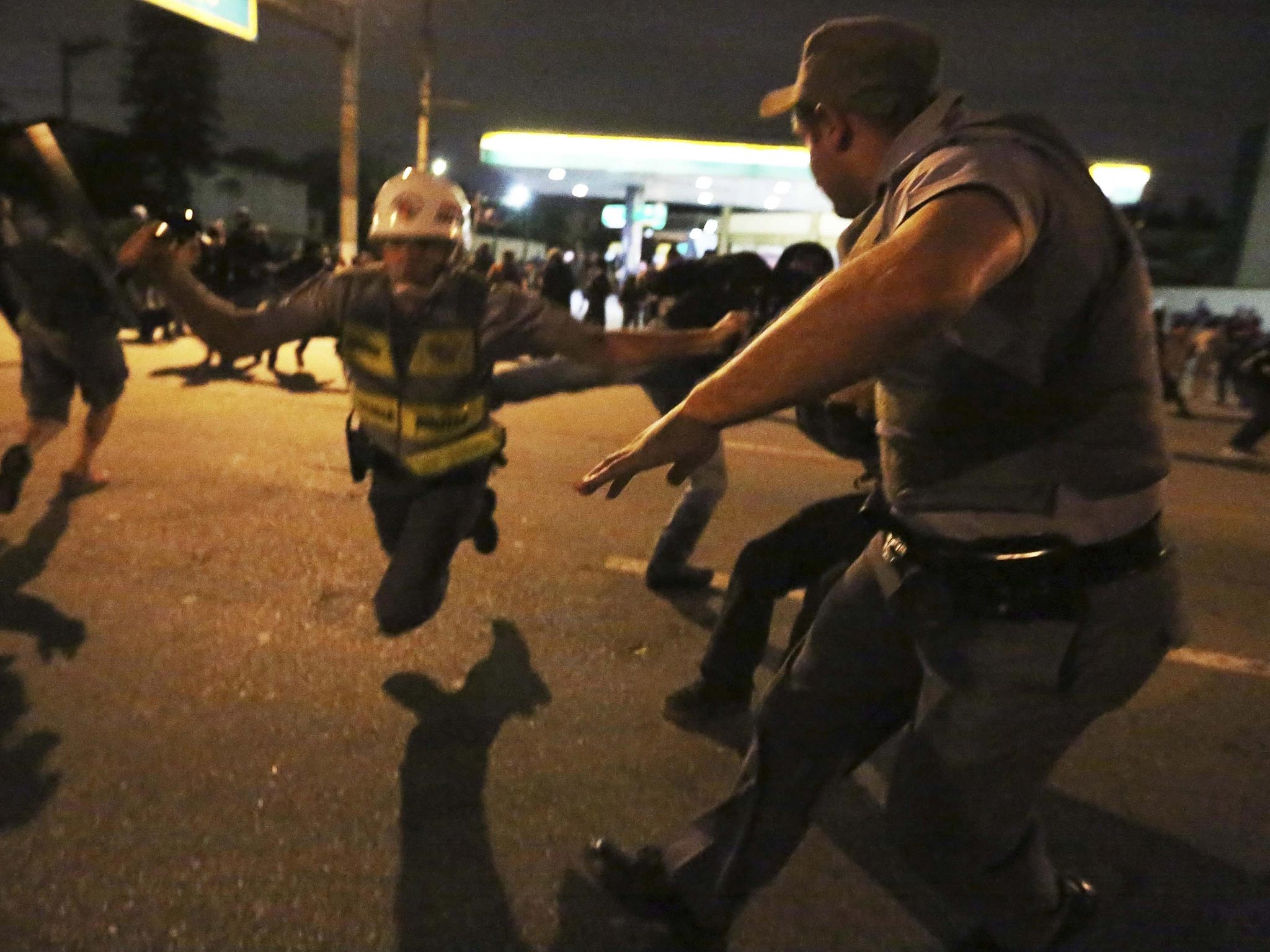 A demonstrator (rear right) from the group called Black Bloc kicks a military policeman during a protest supporting a teachers' strike in Sao Paulo