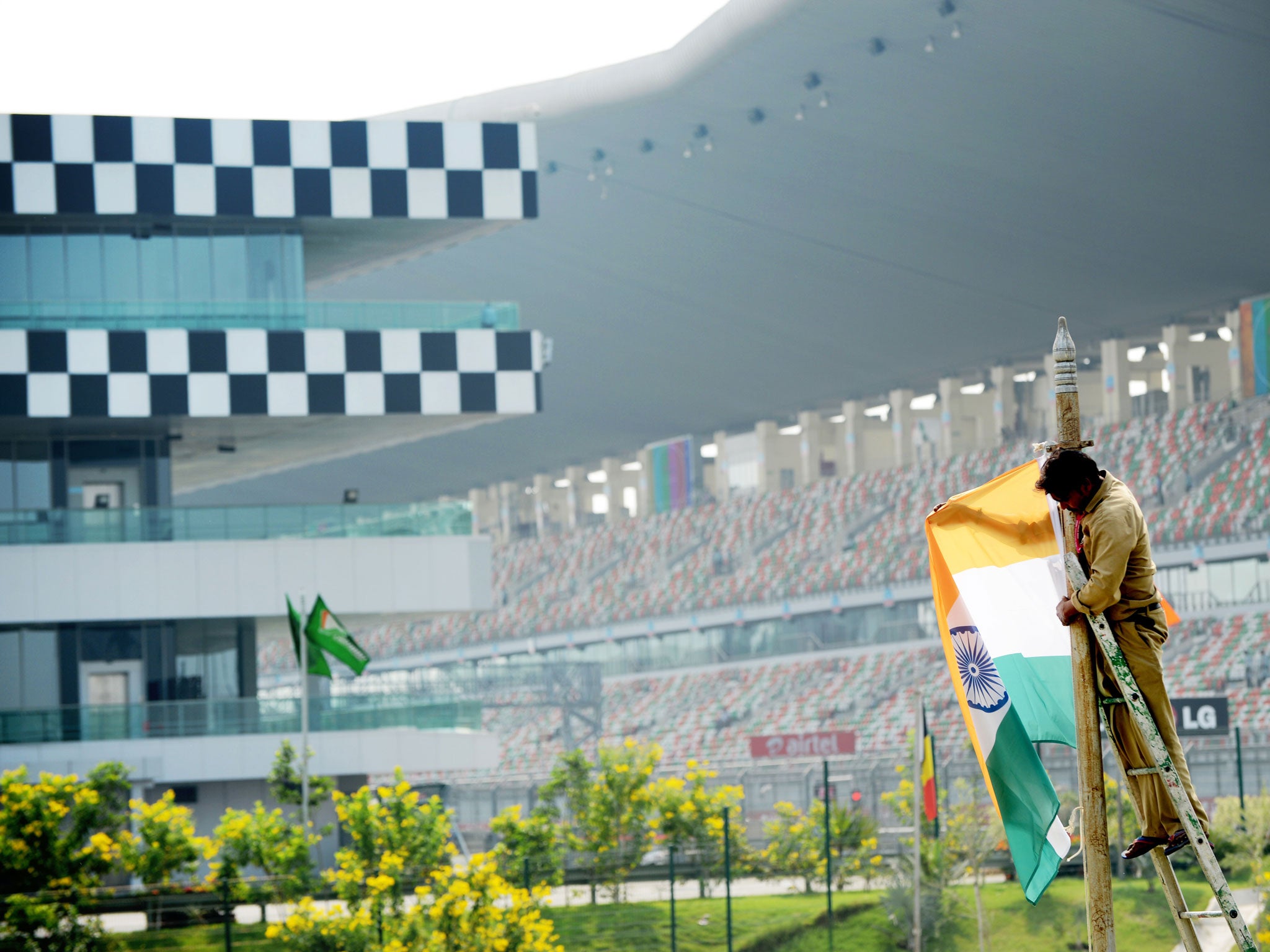 A worker hangs an Indian flag from a post in the grounds of The Buddh International circuit in Greater Noida on the outskirts of New Delhi