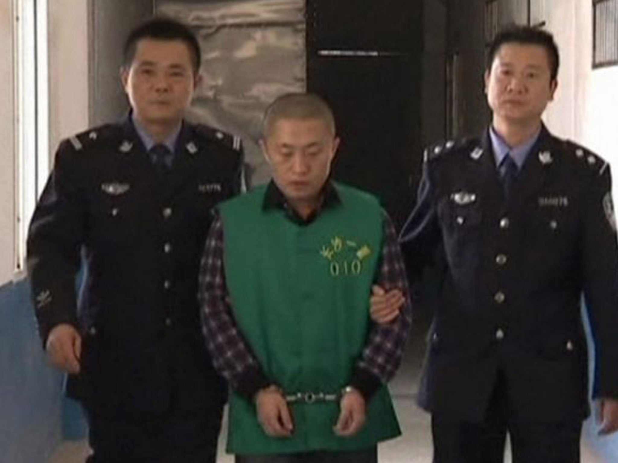 Journalist Chen Yongzhou, in handcuffs, is escorted by police officers at the Changsha Public Security Bureau detention centre in Changsha City, Hunan Province, in this still image taken from China Central Television (CCTV) video shot on 25 October, 2013