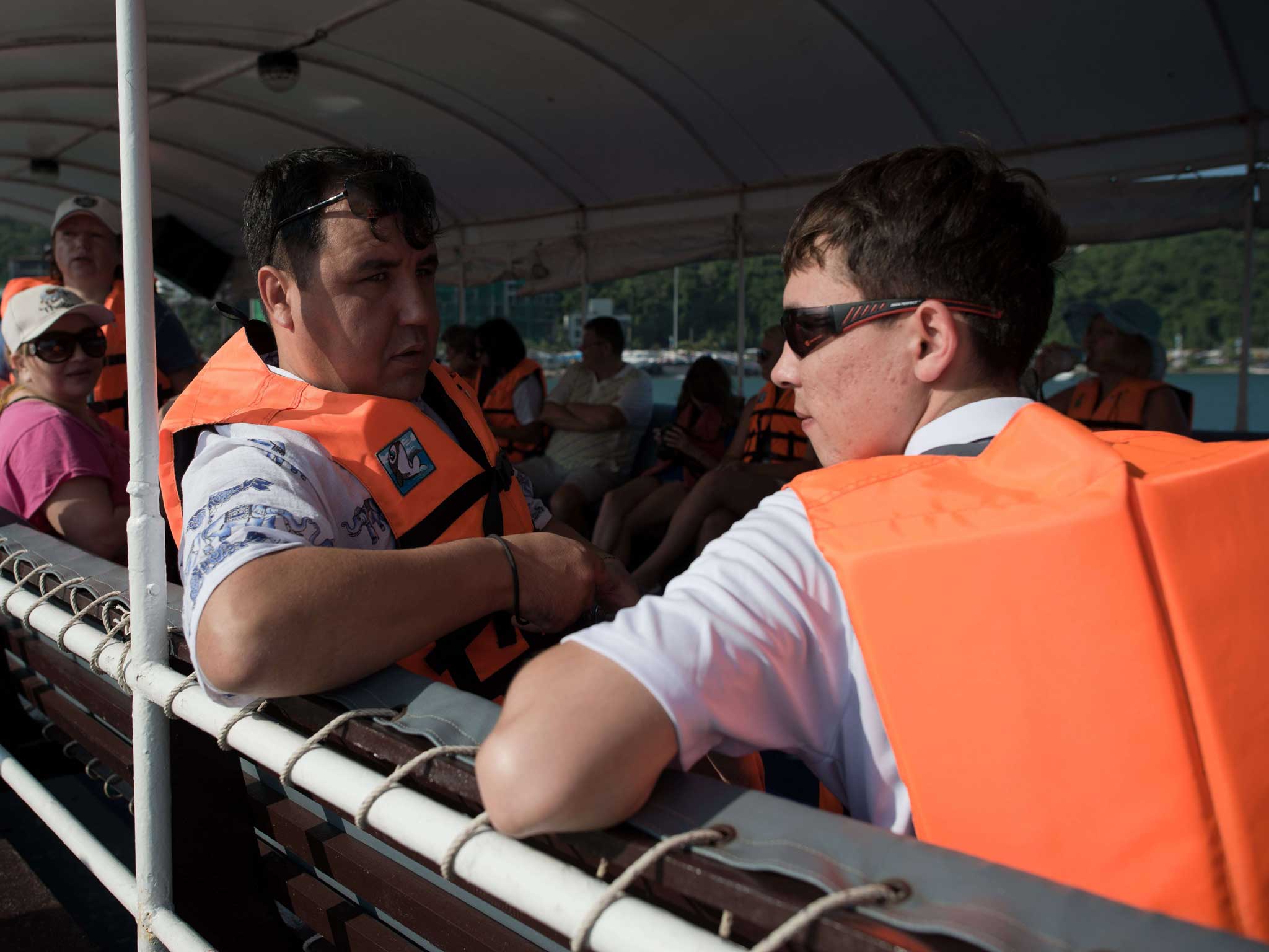 Tourists sit with life jackets on a double-decker boat ahead of its departure from a pier in Pattaya