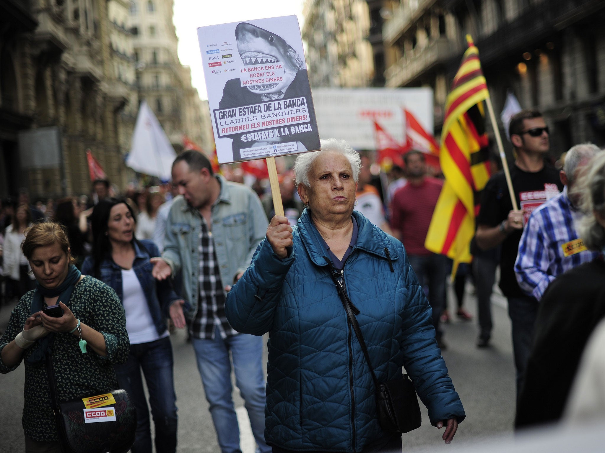 A protester carries a banner reading 'The bank has stolen our money'