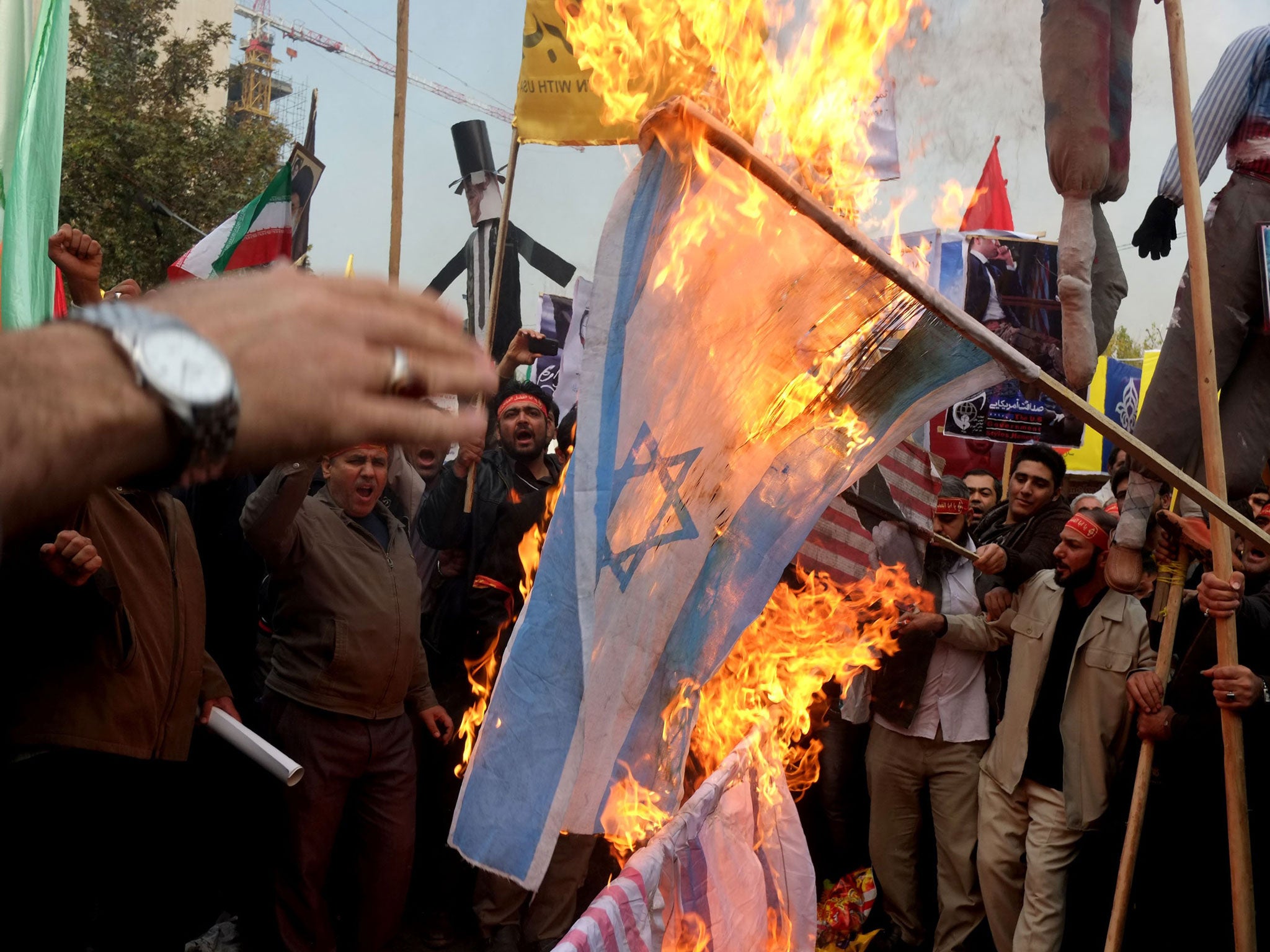 People burn Israel and U.S. flags a demonstration to mark the 34th anniversary of the 1979 US embassy takeover