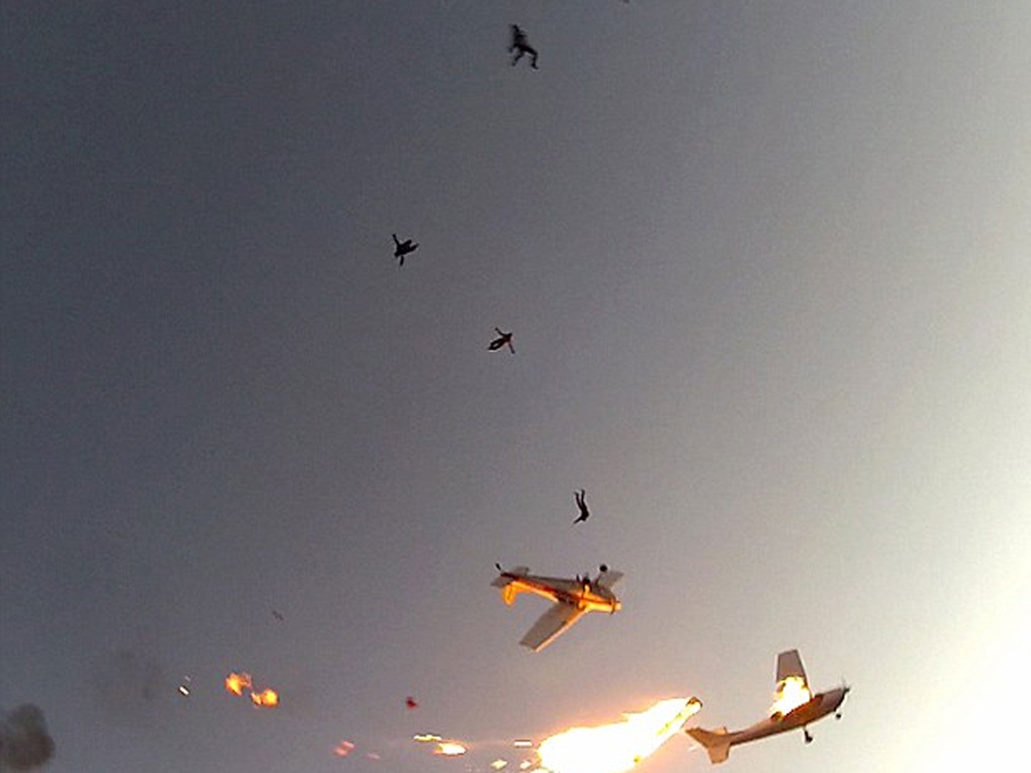 Skydivers fall from the sky after the aircraft accidentally collided, causing one to erupt in flames