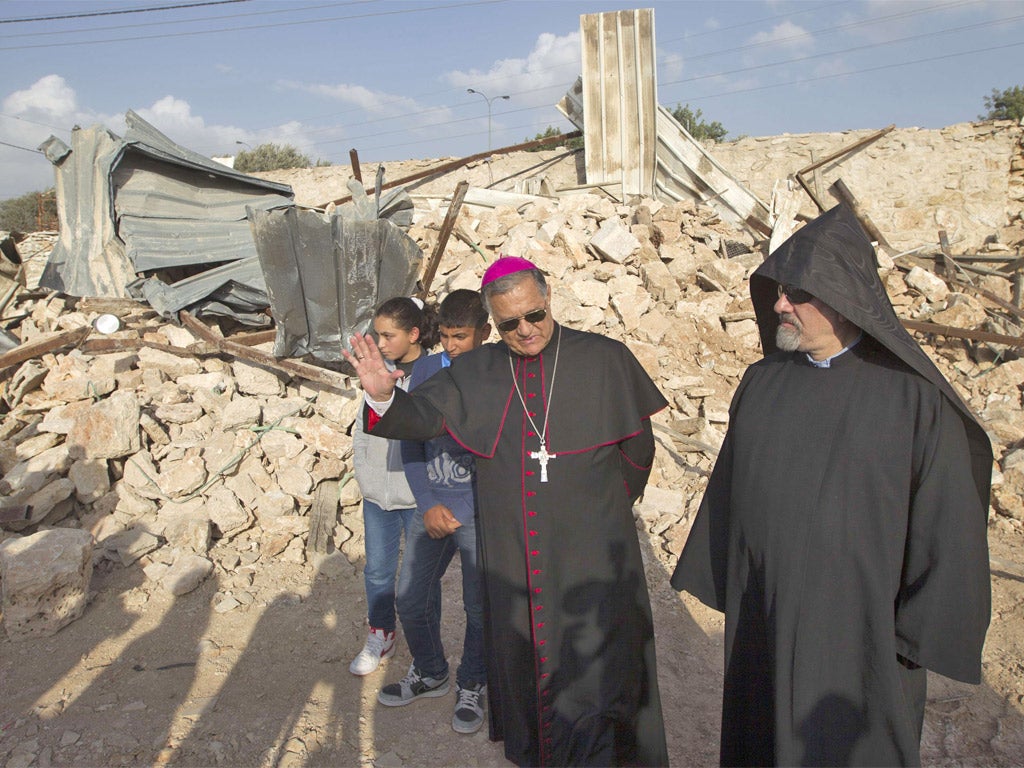 Children look on as Latin Patriarch of Jerusalem Fouad Twal (centre) stands amongst the ruins of a Palestinian home a week after it was demolished by the Israeli authority in East Jerusalem