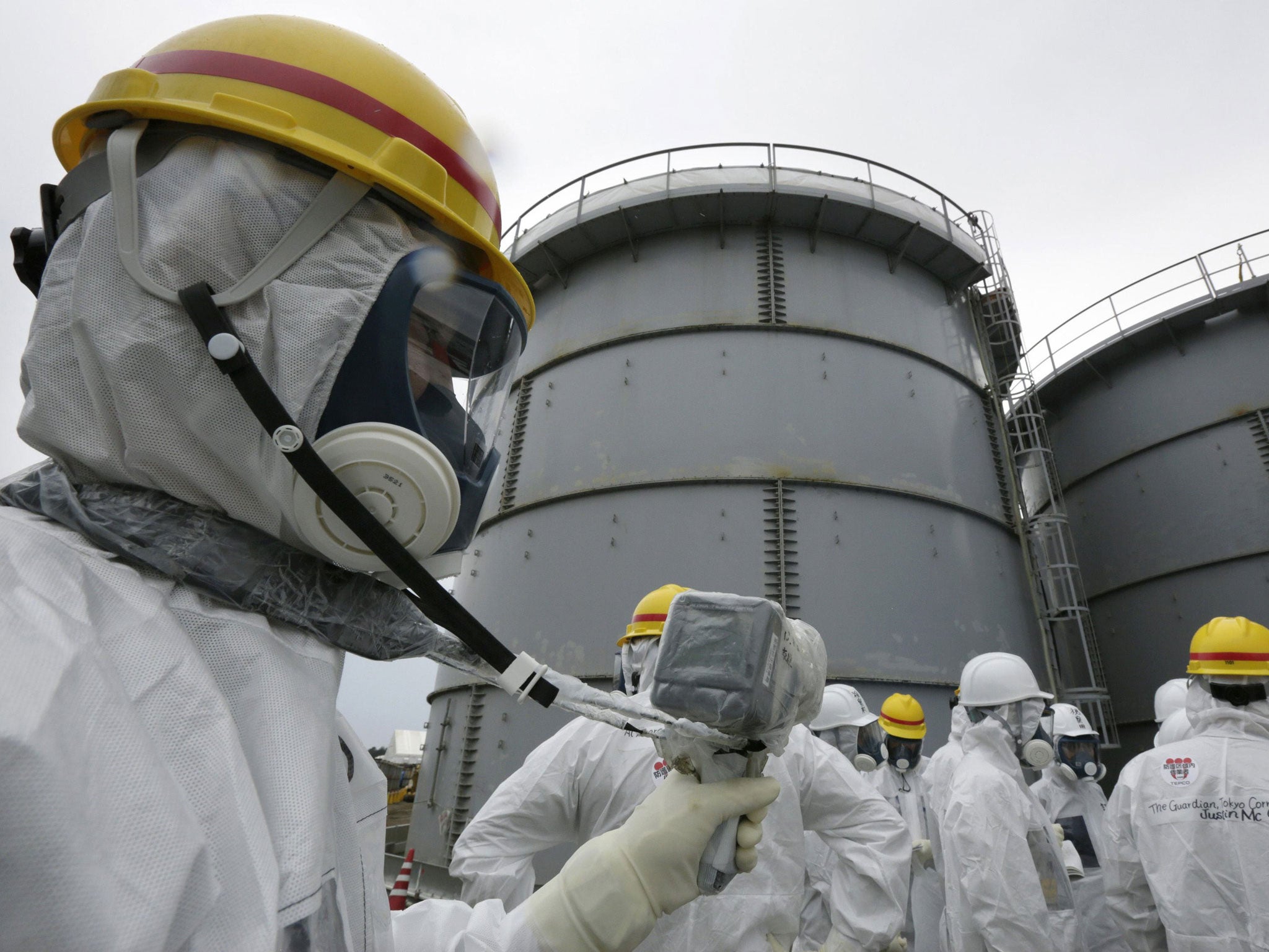 An official monitors radiation levels outside reactor four during a media tour of the Fukushima nuclear plant