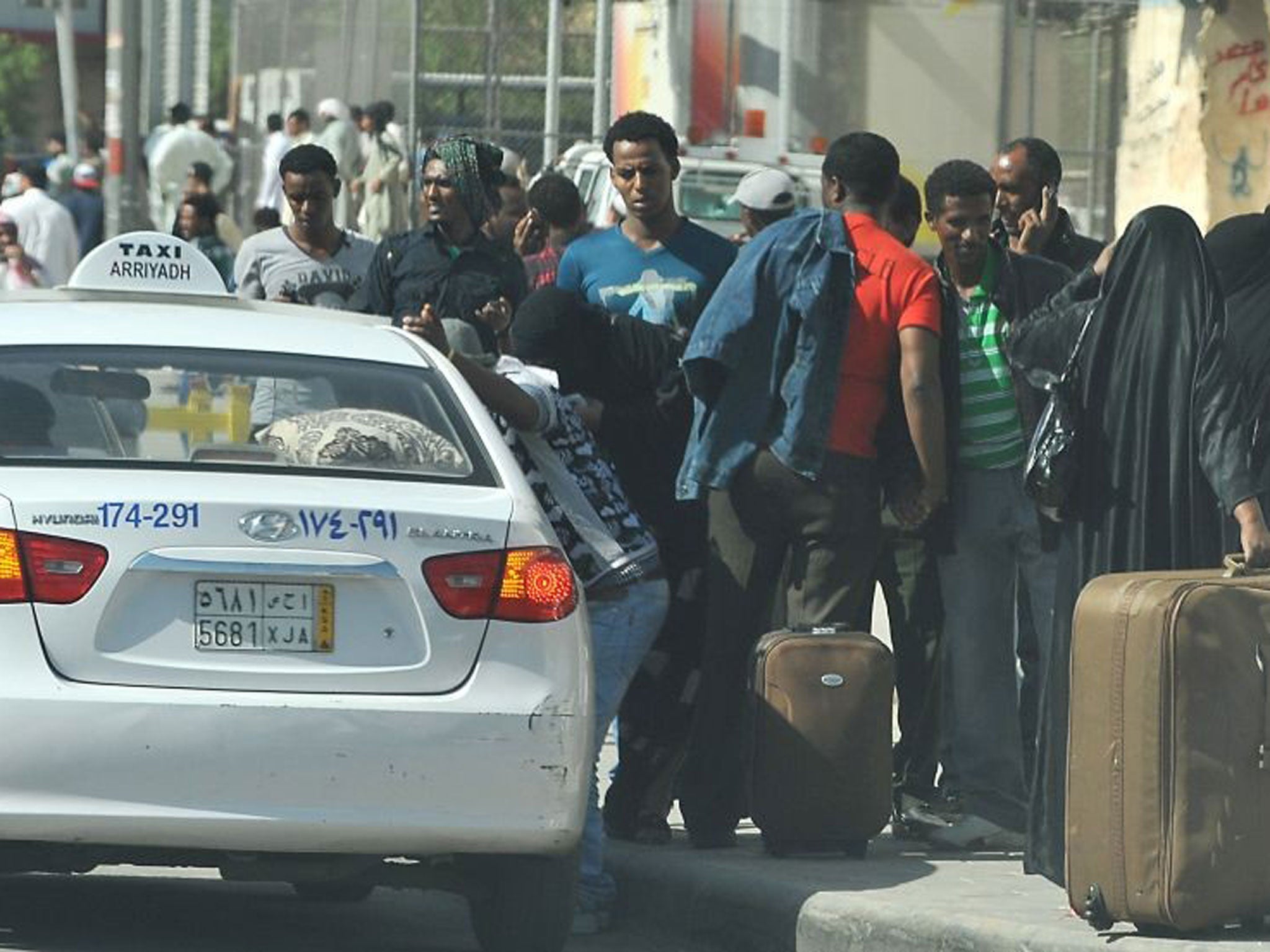 Foreign workers wait for a taxi to leave the Manfuhah neighbourhood of Riyadh on 10 November, after two people have been killed in clashes between Saudi and other foreign residents the previous day