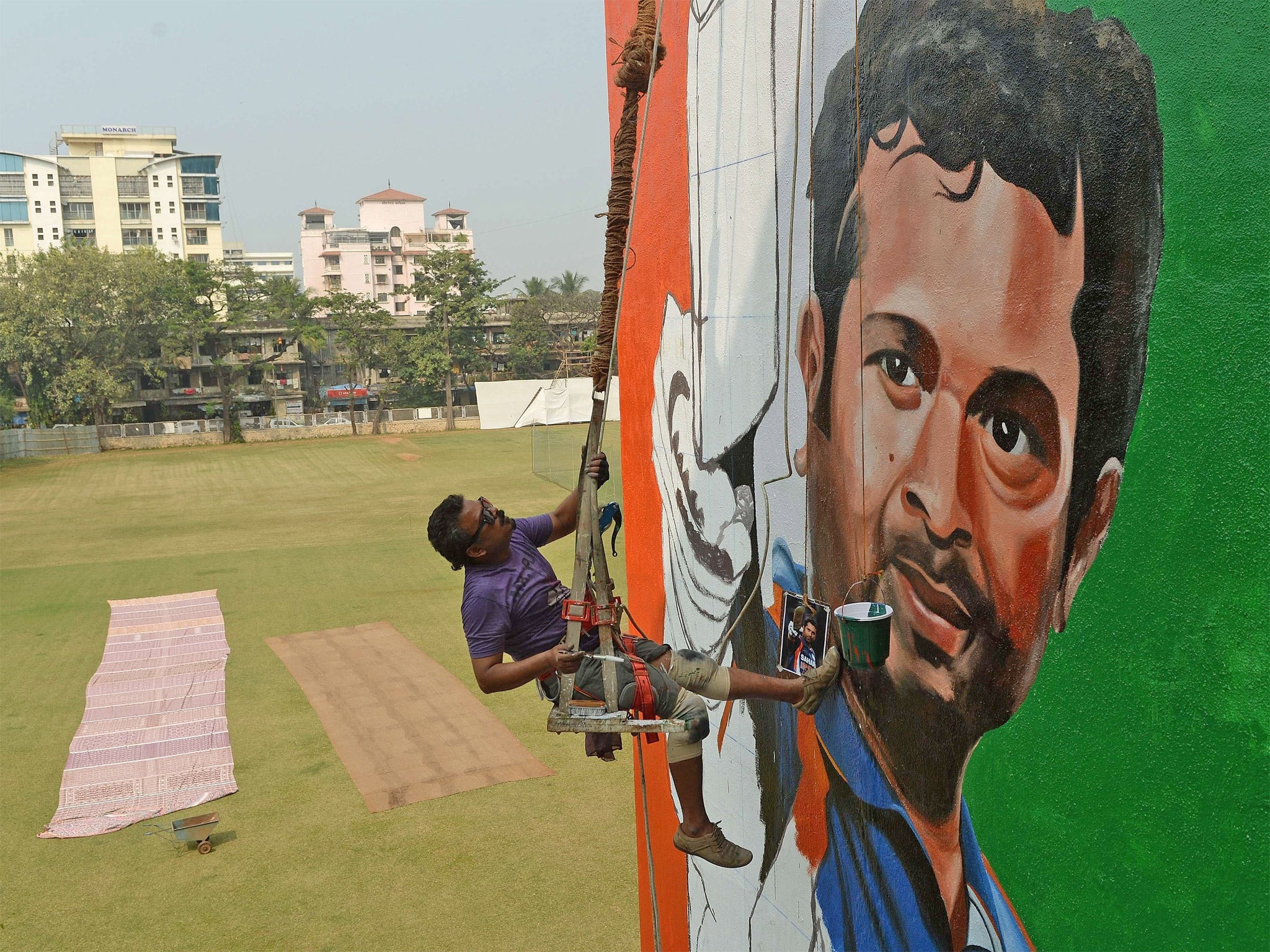 Indian artist Ranjit Dahiya braves the heights as Mumbai prepares for the start of Tendulkar’s final Test match (Getty)