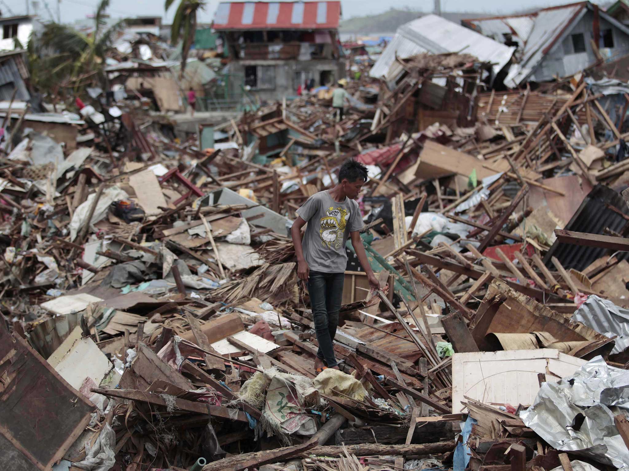 A Filipino man walks among debris from damaged homes in typhoon-hit Tacloban city