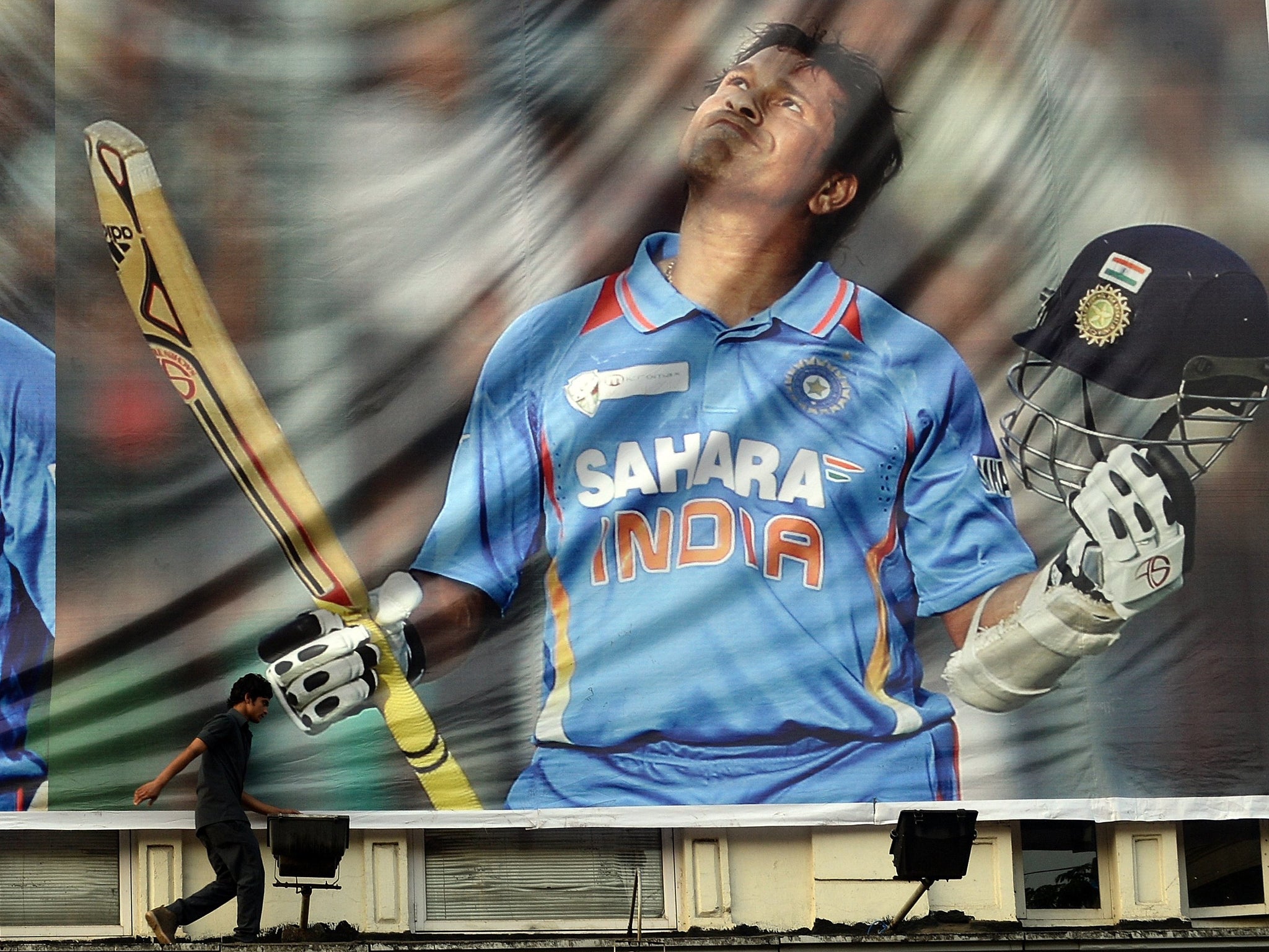 A young fan walks past a billboard paying tribute to Sachin Tendulkar