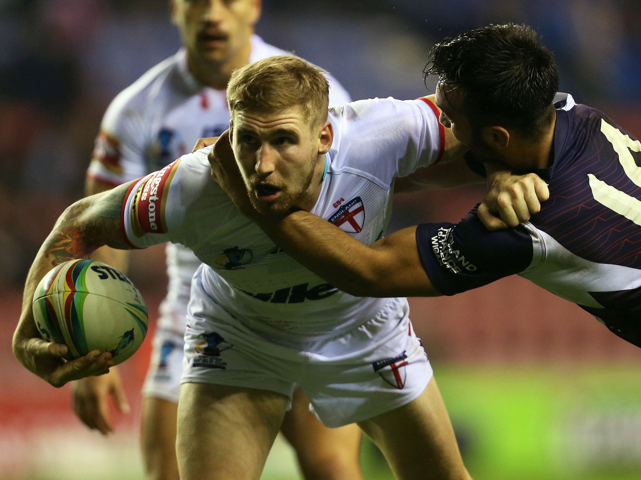 England’s Sam Tomkins, left, is tackled by France’s Éloi Pélissier, right