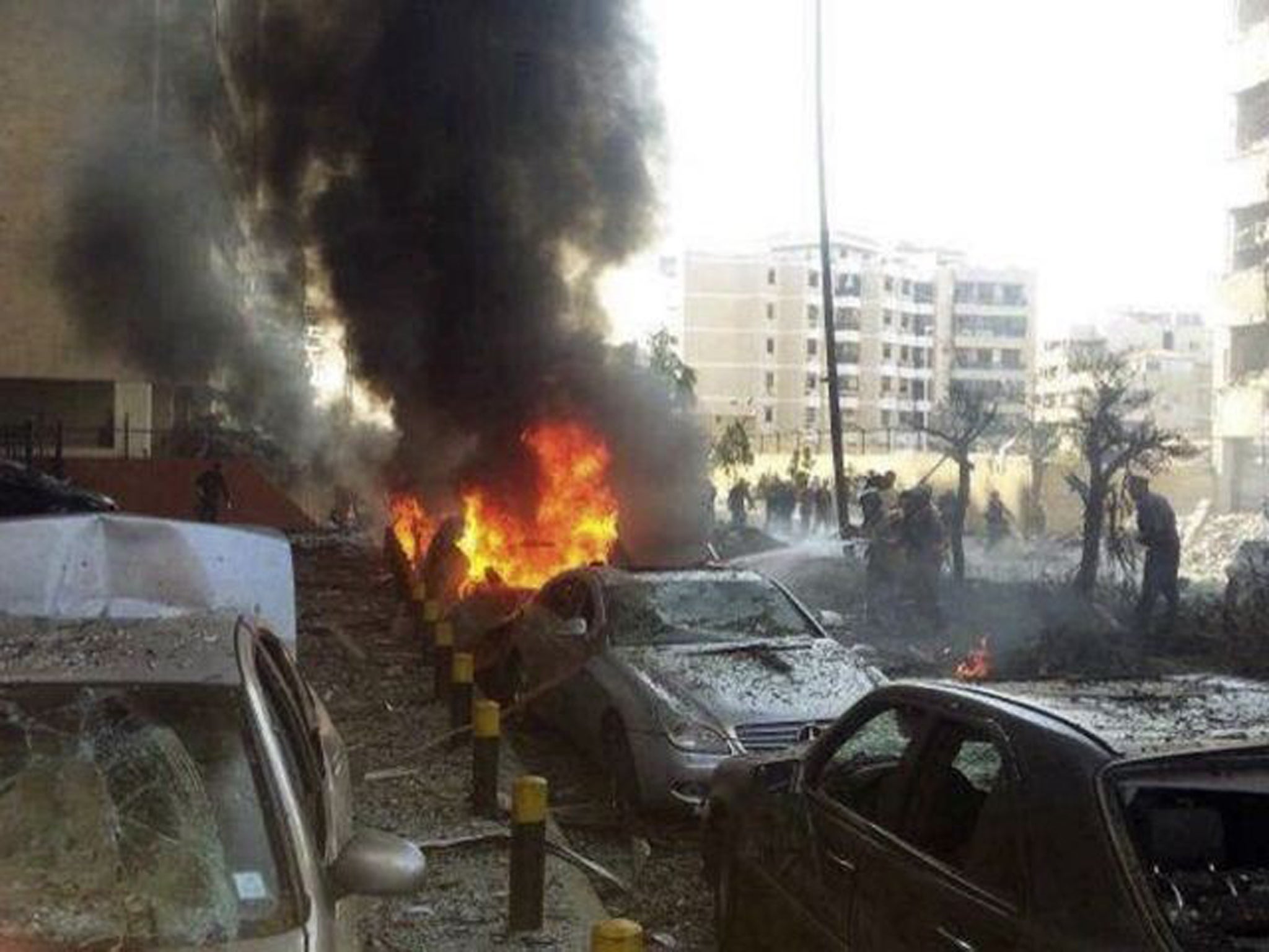 Civil Defence personnel extinguish a fire at the site of the explosions near the Iranian embassy in Beirut