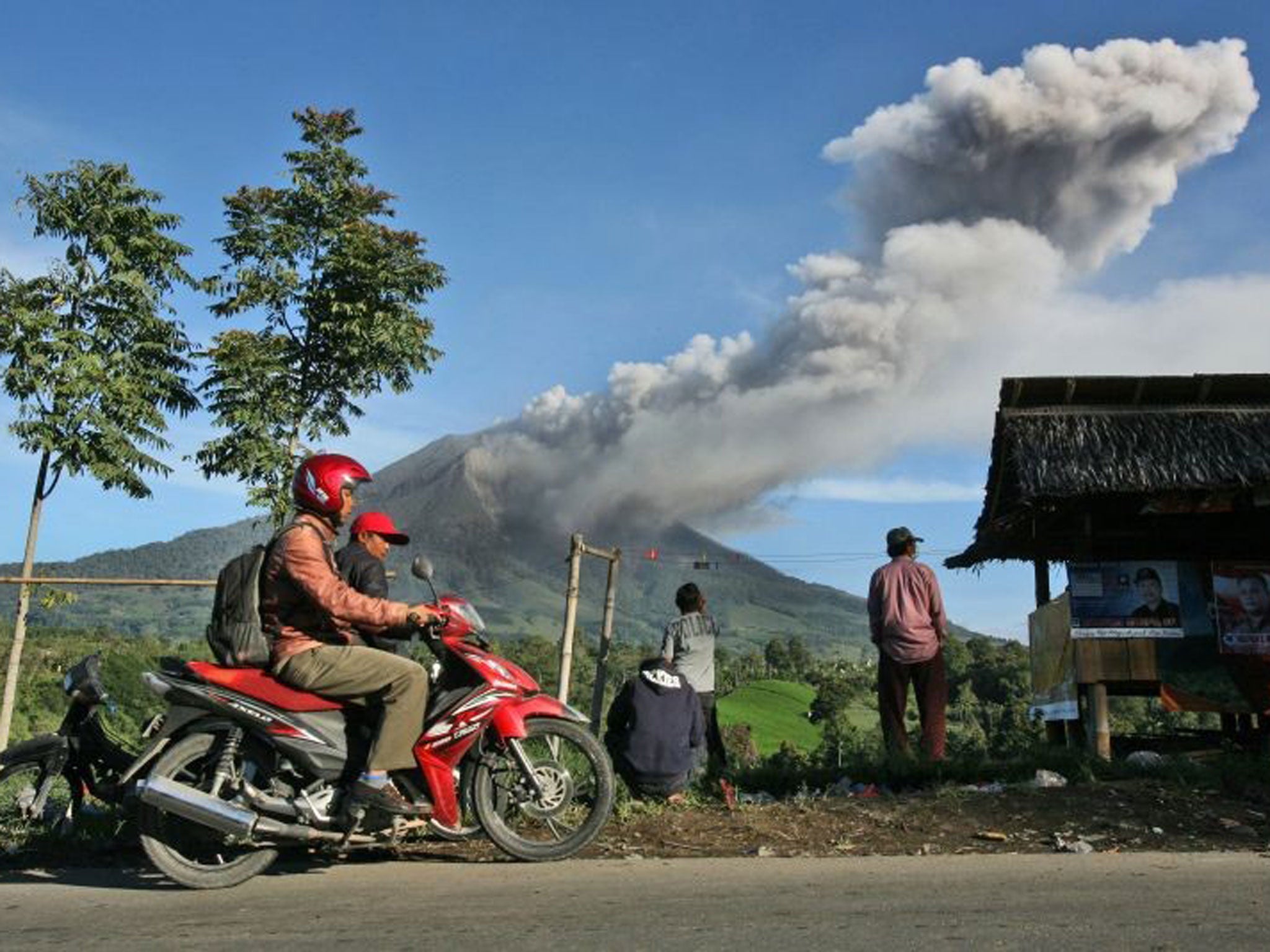 Villagers watch Mount Sinabung spewing volcanic ash into in Tiga Pancur, North Sumatra, Indonesia