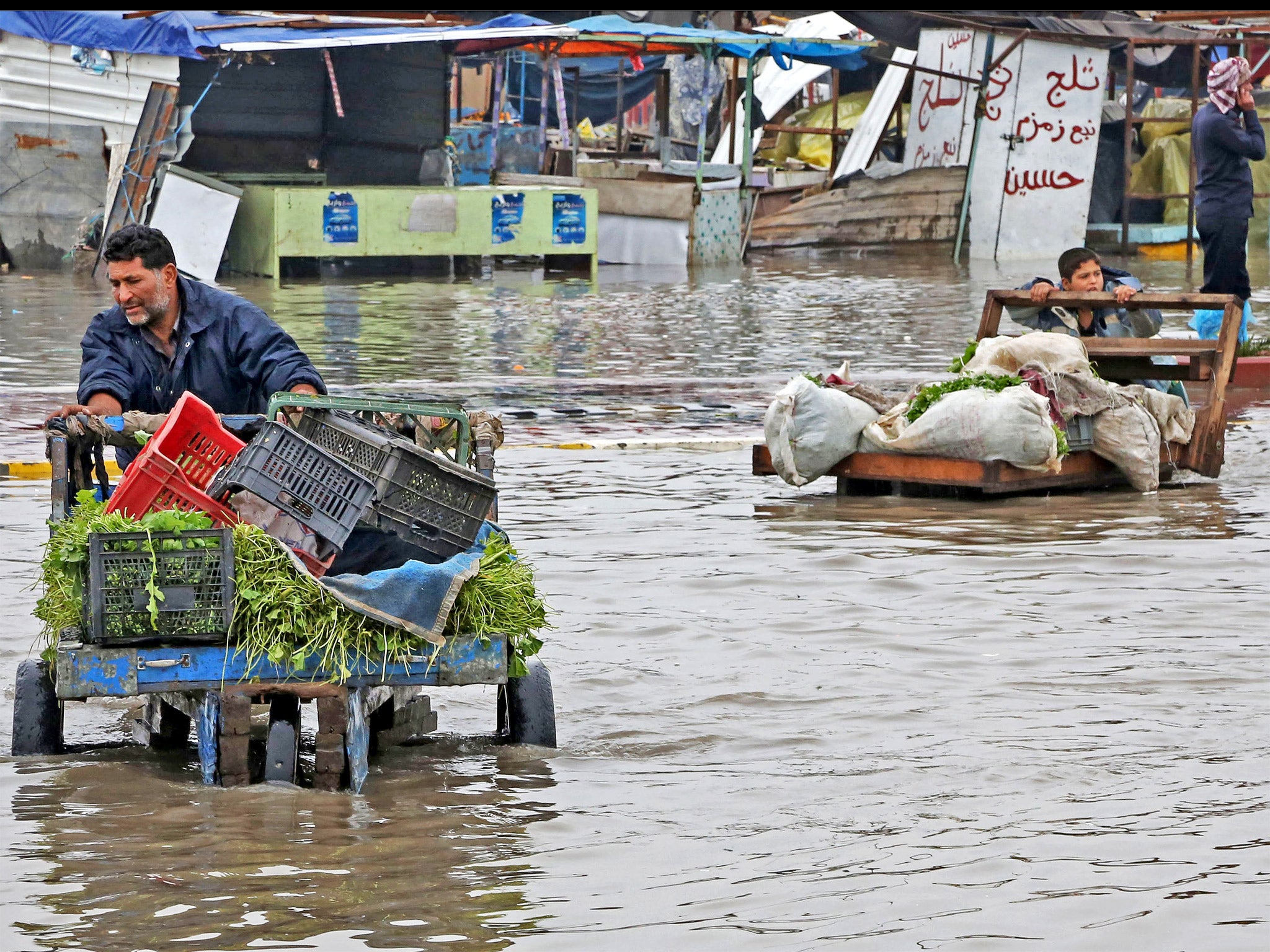 Street vendors push their carts as they make their way through a flooded street