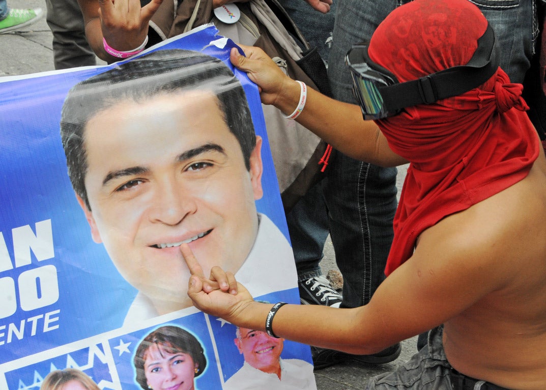 A supporter of the Libertad y Refundacion (LIBRE), throws the finger to propaganda of the Honduran presidential candidate for the Partido Nacional, Juan Orlando Hernandez, during protests this week