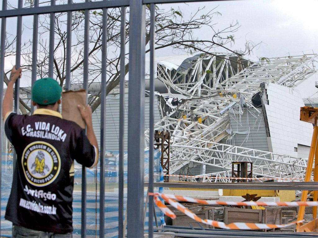 A fan inspects the damage at the partly finished Arena Corinthians in Sao Paulo, where two people died in an accident