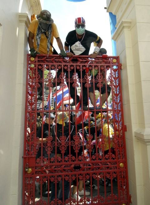 Thai anti-government protesters climb a gate into the Royal Thai Army Headquarters in Bangkok, Thailand