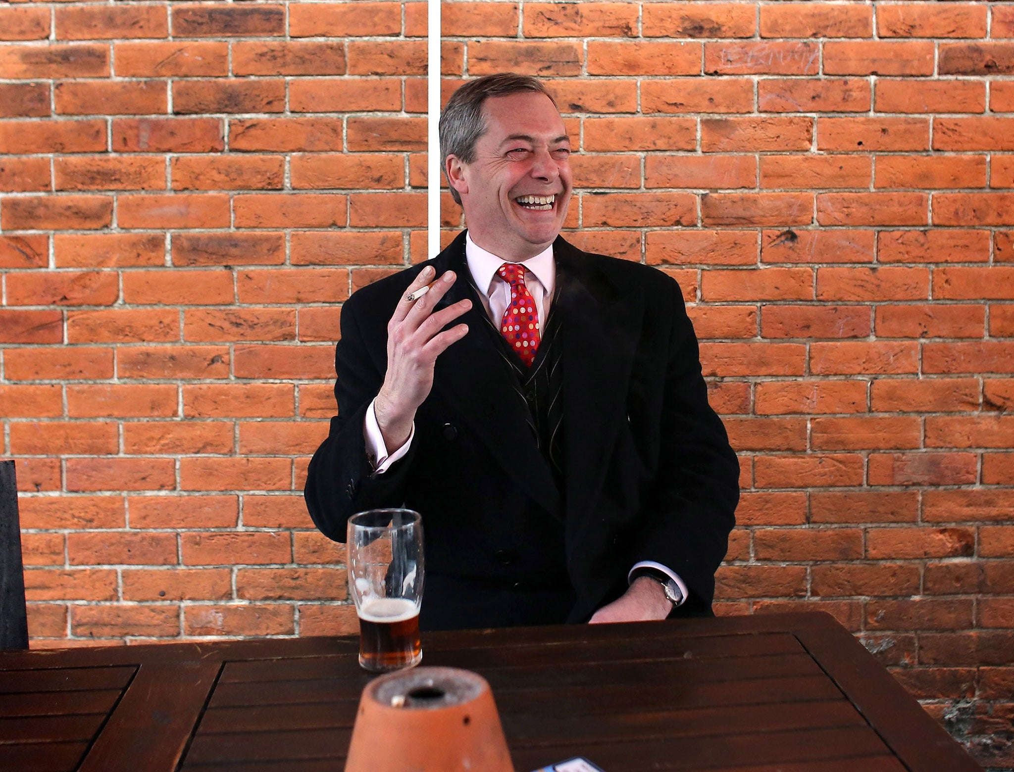 Nigel Farage smokes a cigarette and drinks a pint of beer as he takes a break in a pub during the by-election campaign for Eastleigh, Hampshire