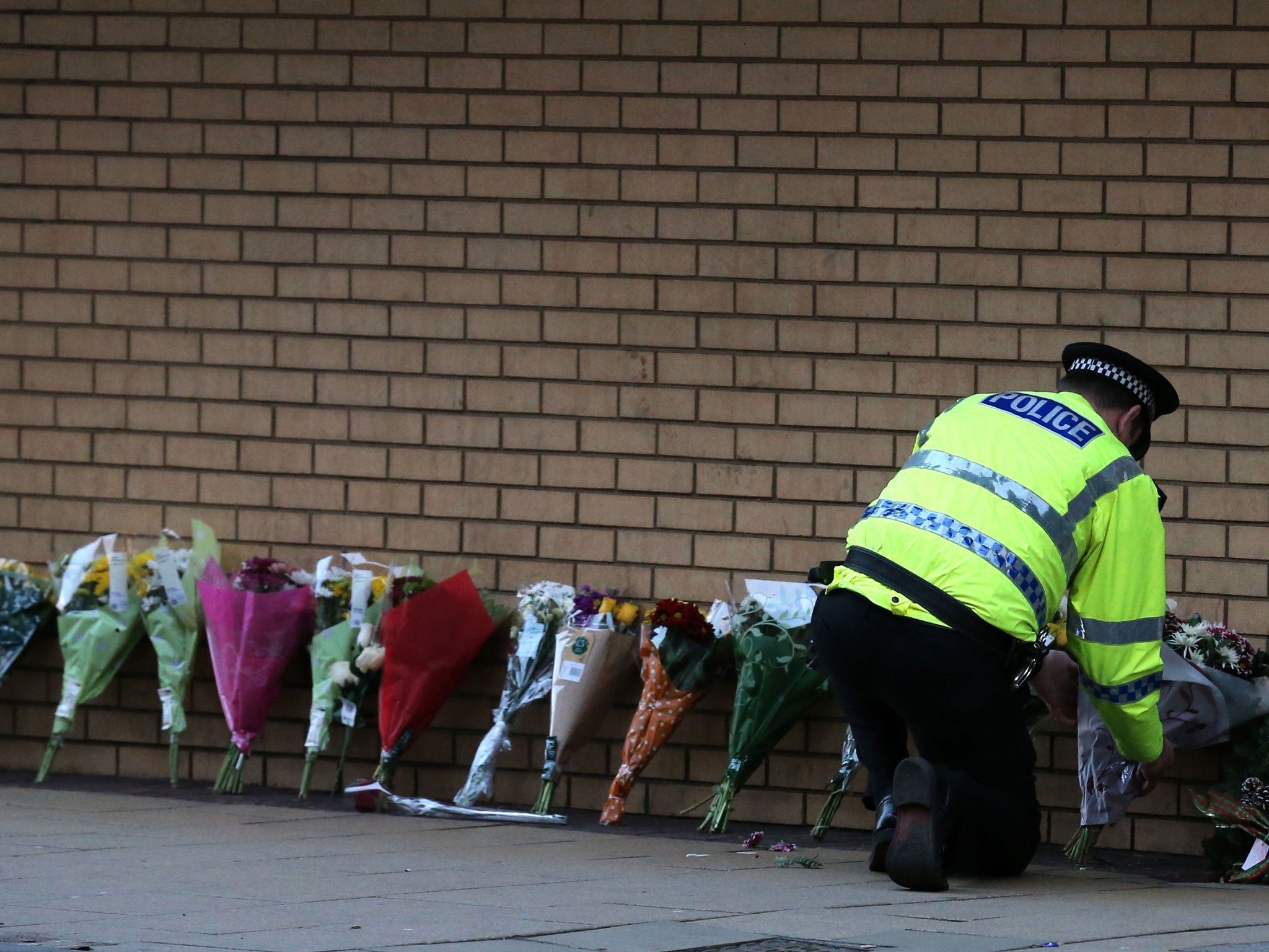 A police officer lays flowers near the scene of a helicopter crash in Glasgow city centre