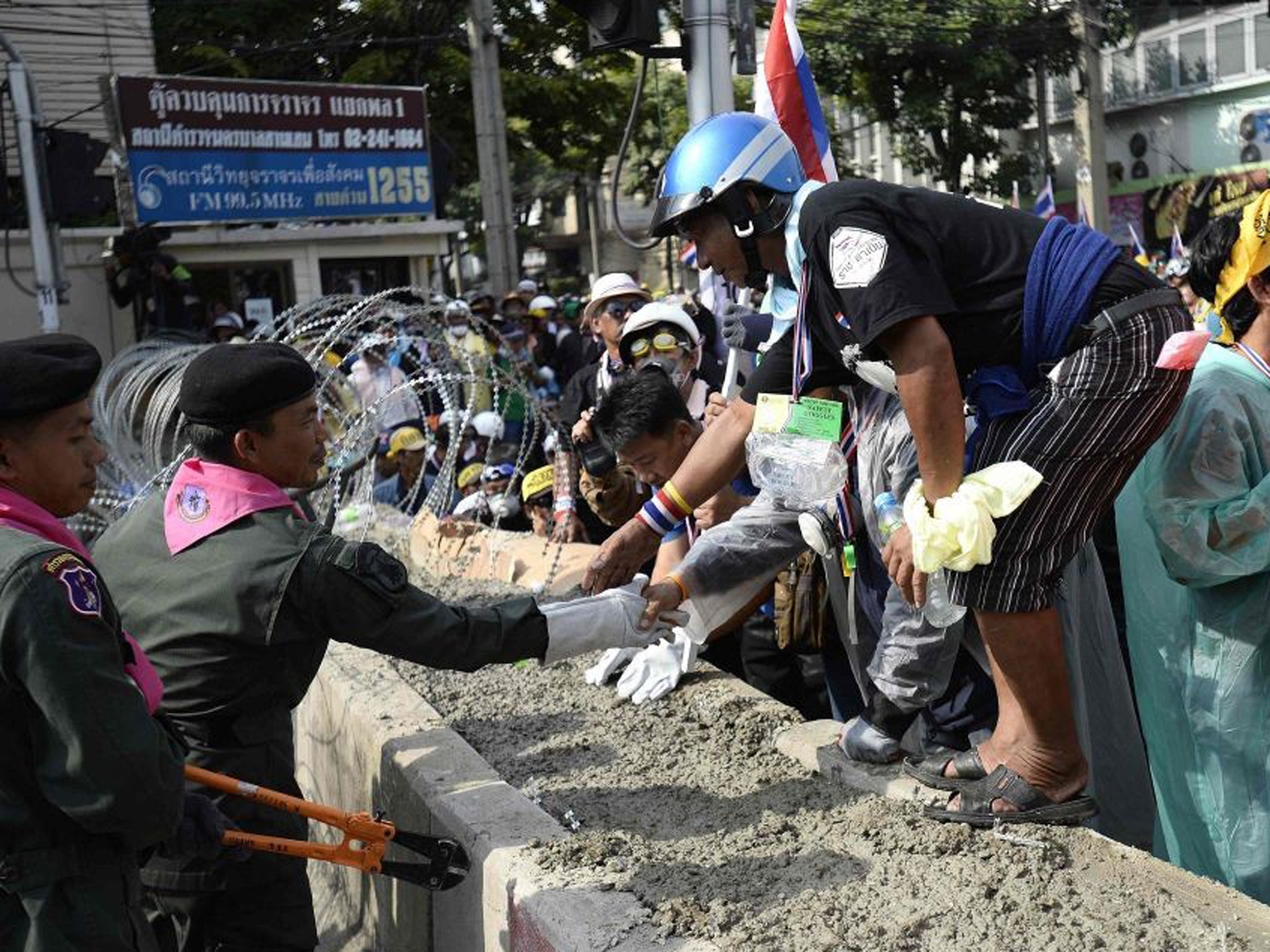 Thai riot police greet anti-government protesters as they welcome them inside their cordon