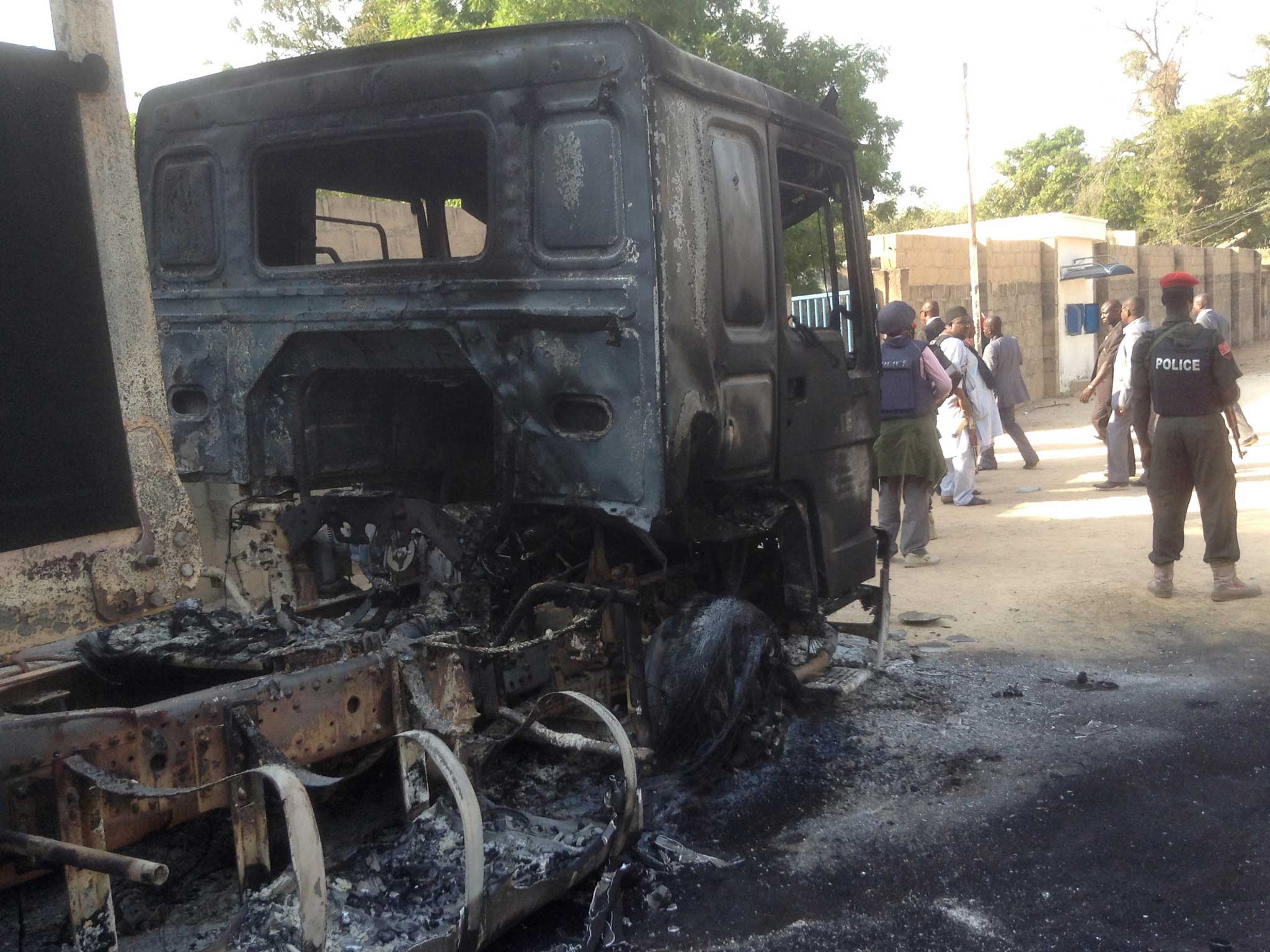 Policemen stand guard at a burnt-out truck following the attack