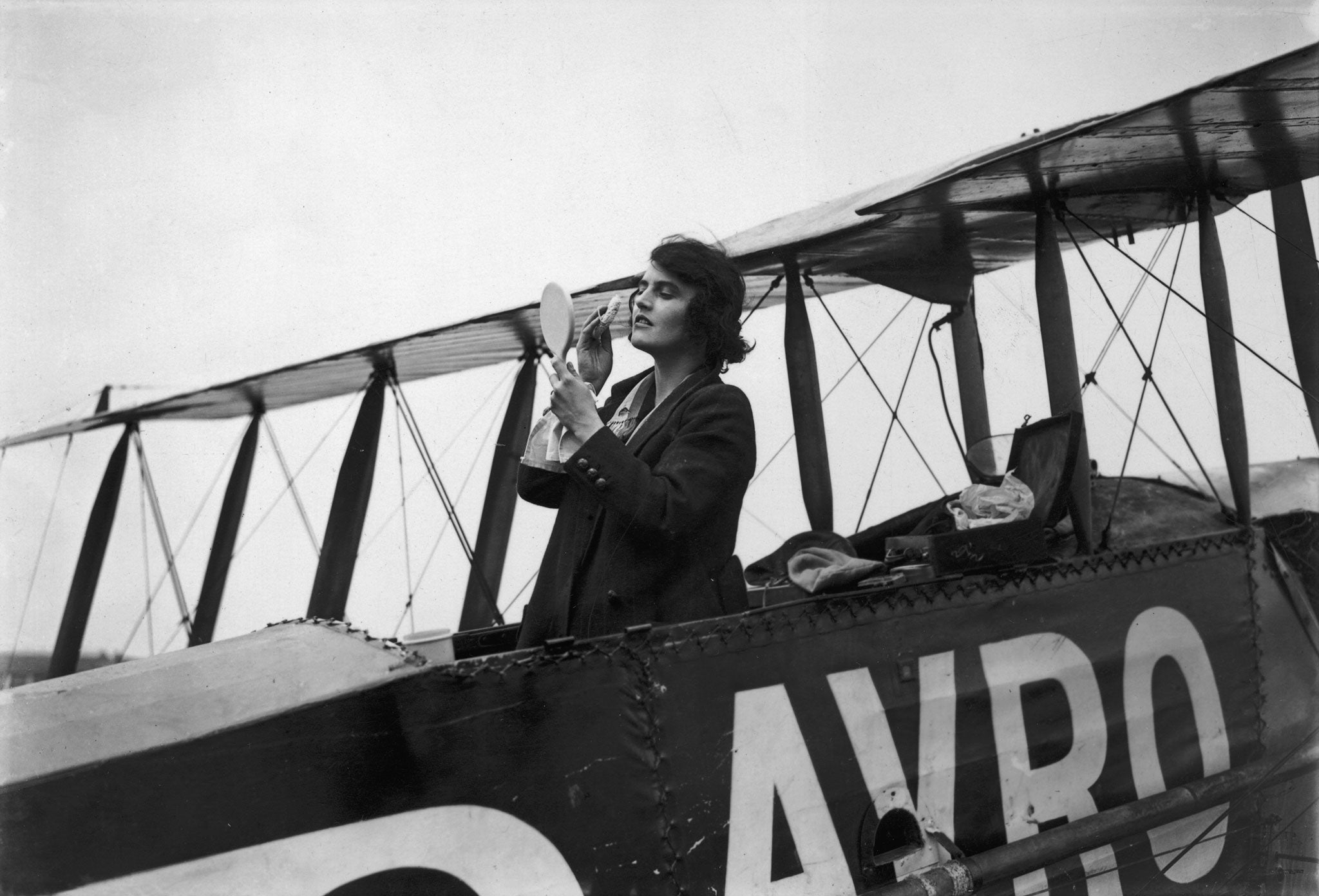 Elsie Mackay applying make-up in the cockpit of her plane, c1920