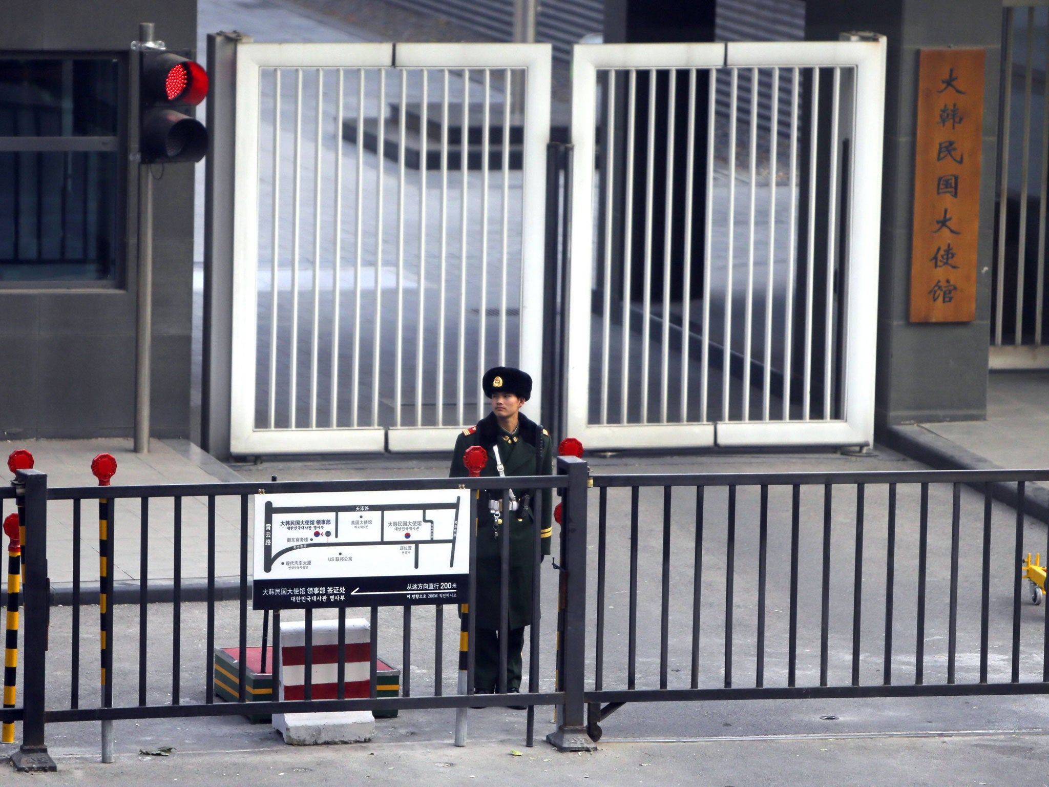 A paramilitary police official stands guard behind a gate at the South Korea embassy in Beijing