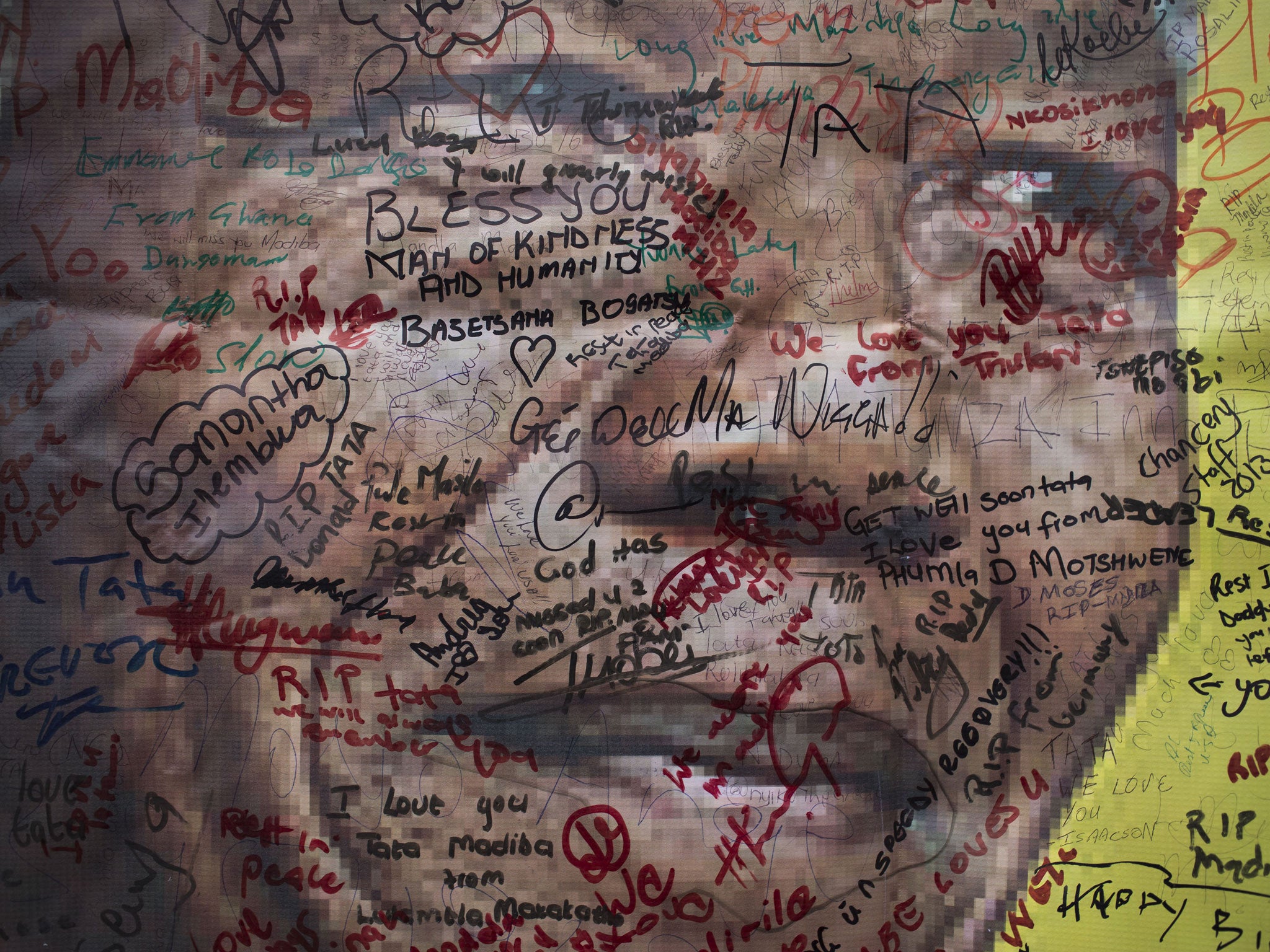 A poster of Nelson Mandela on which mourners have written their messages of condolence and support, in the street outside his old house in Soweto, Johannesburg