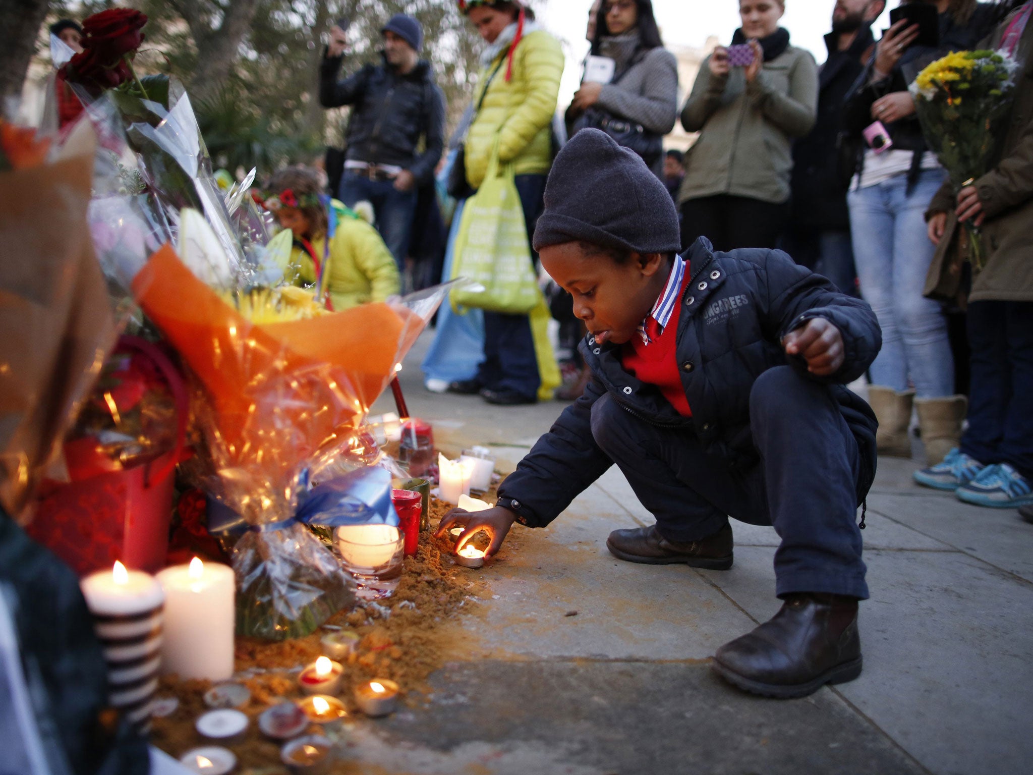 Wenceslous Nicholas, aged four, lights a candle at Mandela’s statue in London’s Parliament Square where flowers, messages and a flag adorn it