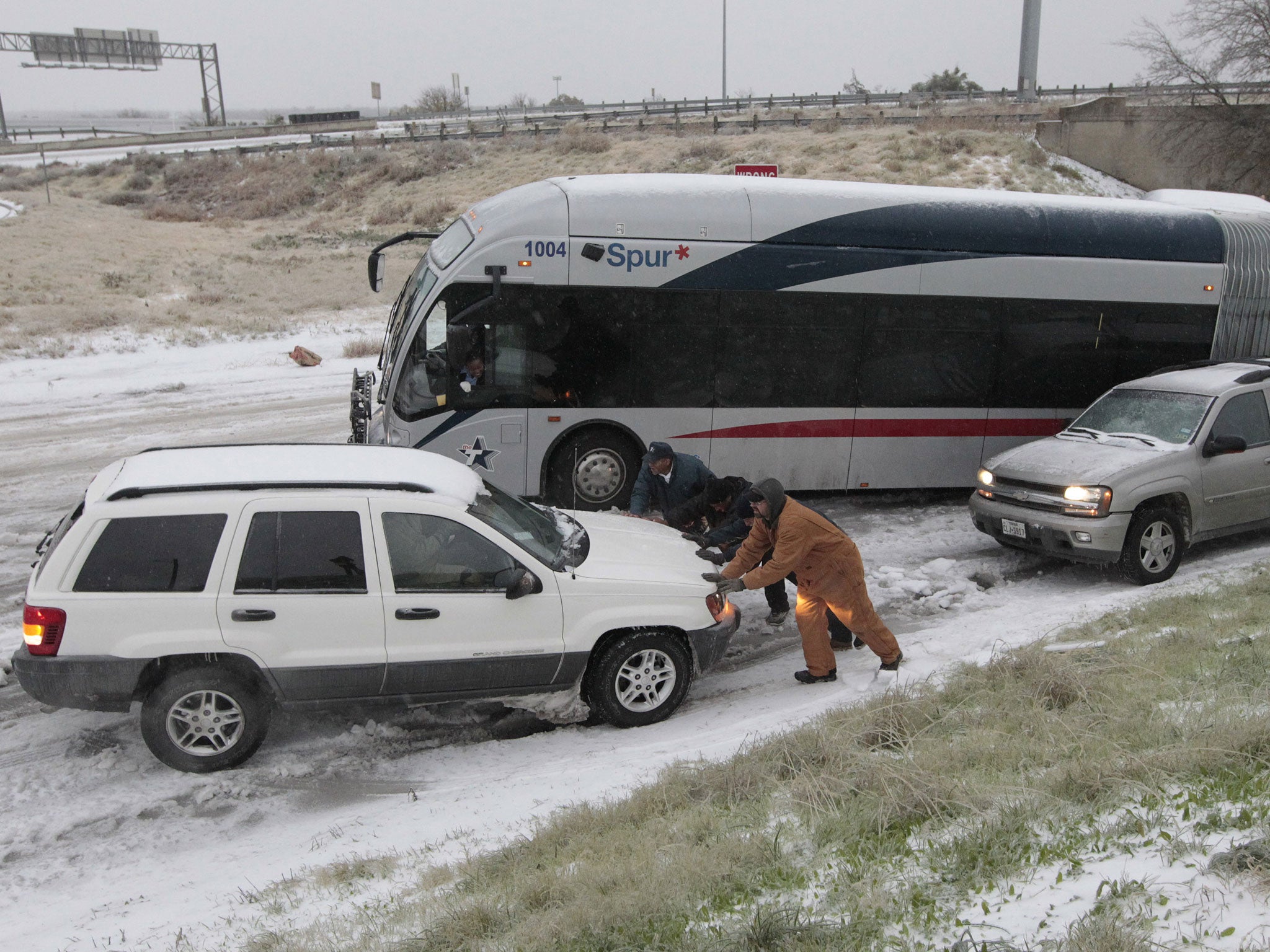 Motorists try to get vehicles and a jack-knifed city bus up an icy hill on East Lancaster Ave. in Fort Worth, Texas
