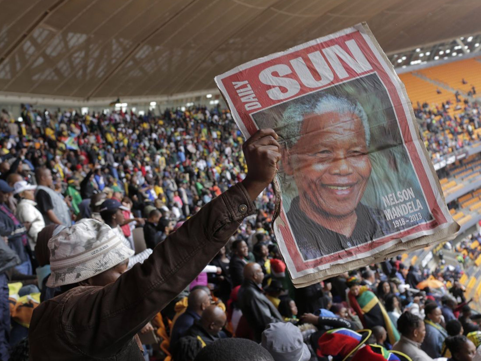 A mourner holds up a copy of South Africa's The Sun newspaper at the FNB Stadium in Soweto
