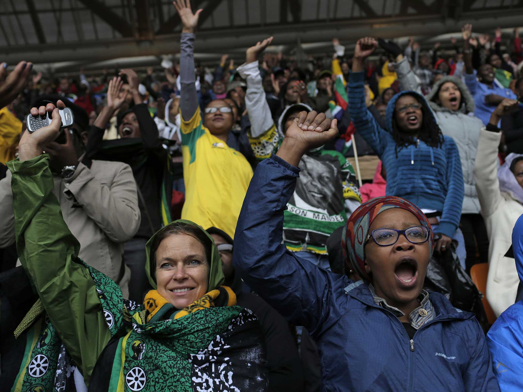 People shout out and punch the air during the memorial service for former South African president Nelson Mandela at the FNB Stadium in Soweto