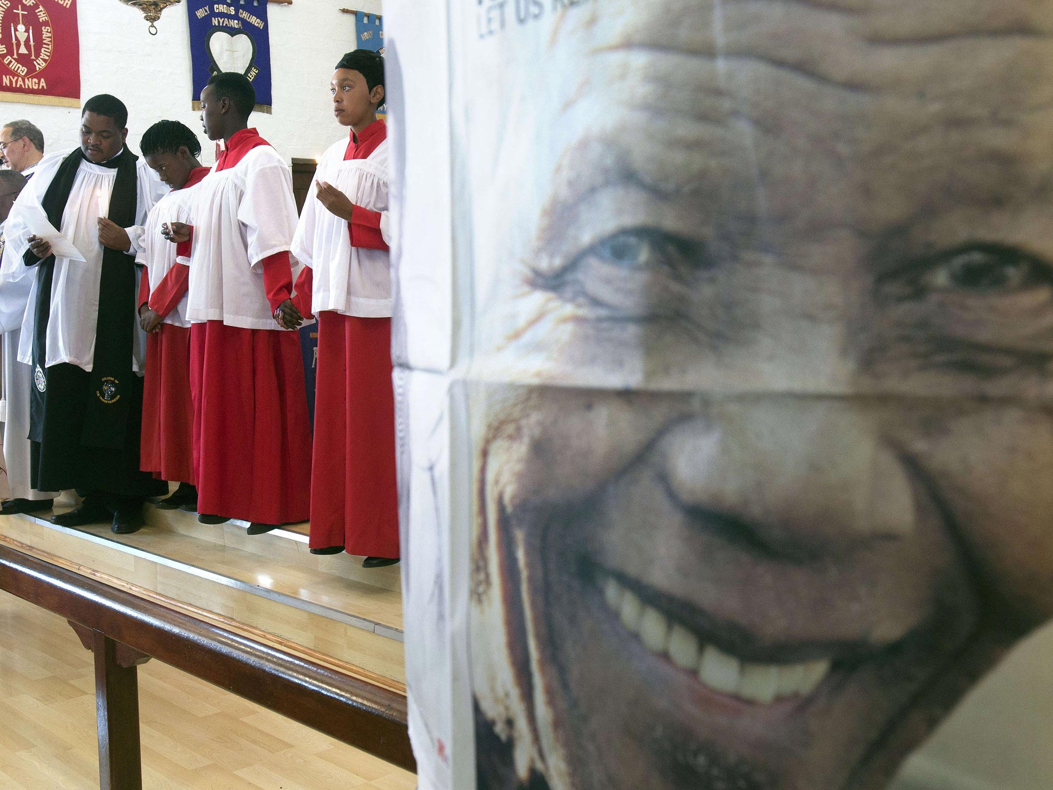 People sing and dance at a prayer service to commemorate the late South African President Nelson Mandela next to a picture of him at Holy Cross Anglican Church in Nyanga, Cape Town,