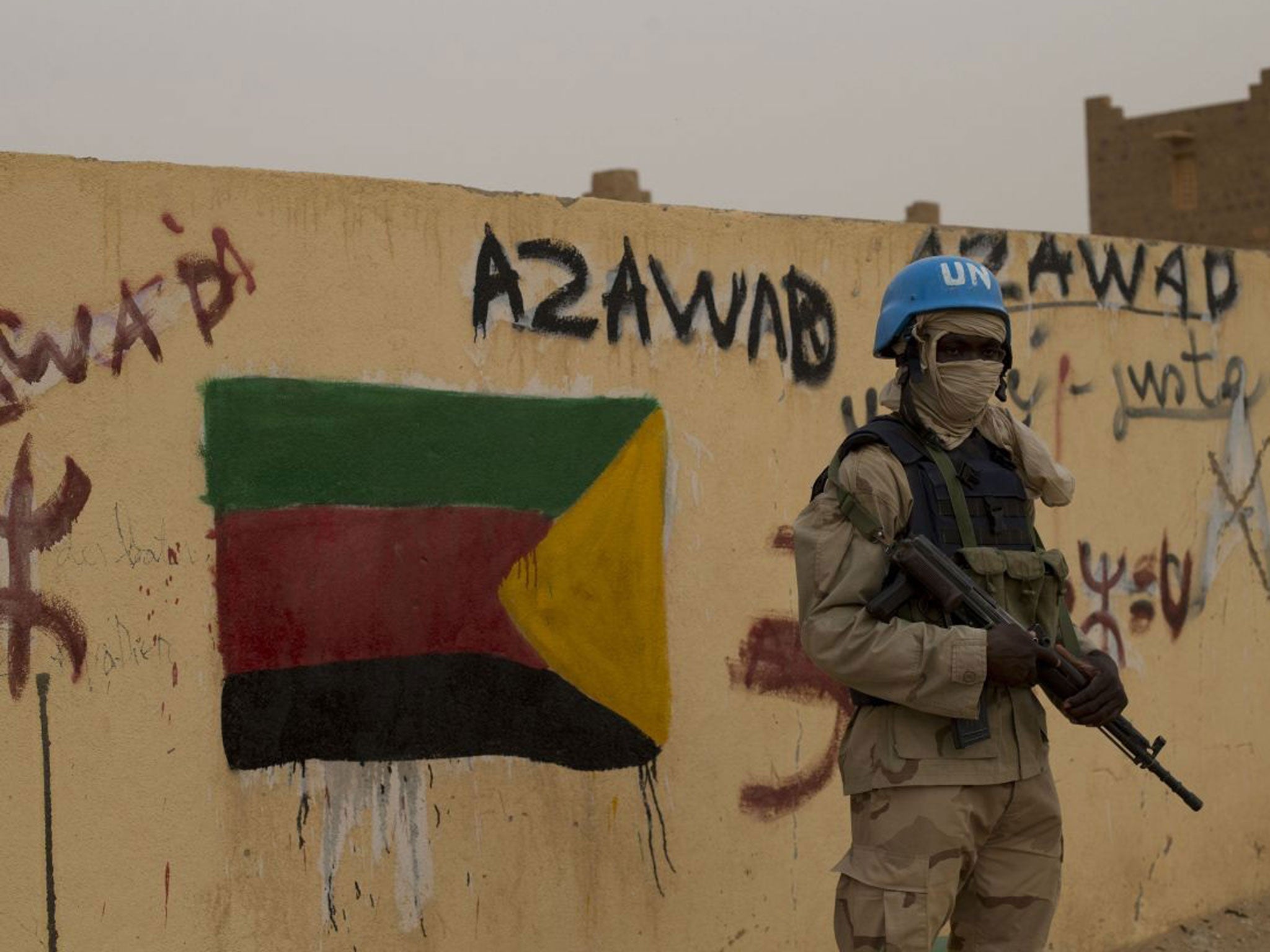 In this Sunday, July, 28, 2013 file photo, a United Nations peacekeeper stands guard at the entrance to a polling station covered in separatist flags and graffiti supporting the creation of the independent state of Azawad, in Kidal, Mali. A bomb explosio