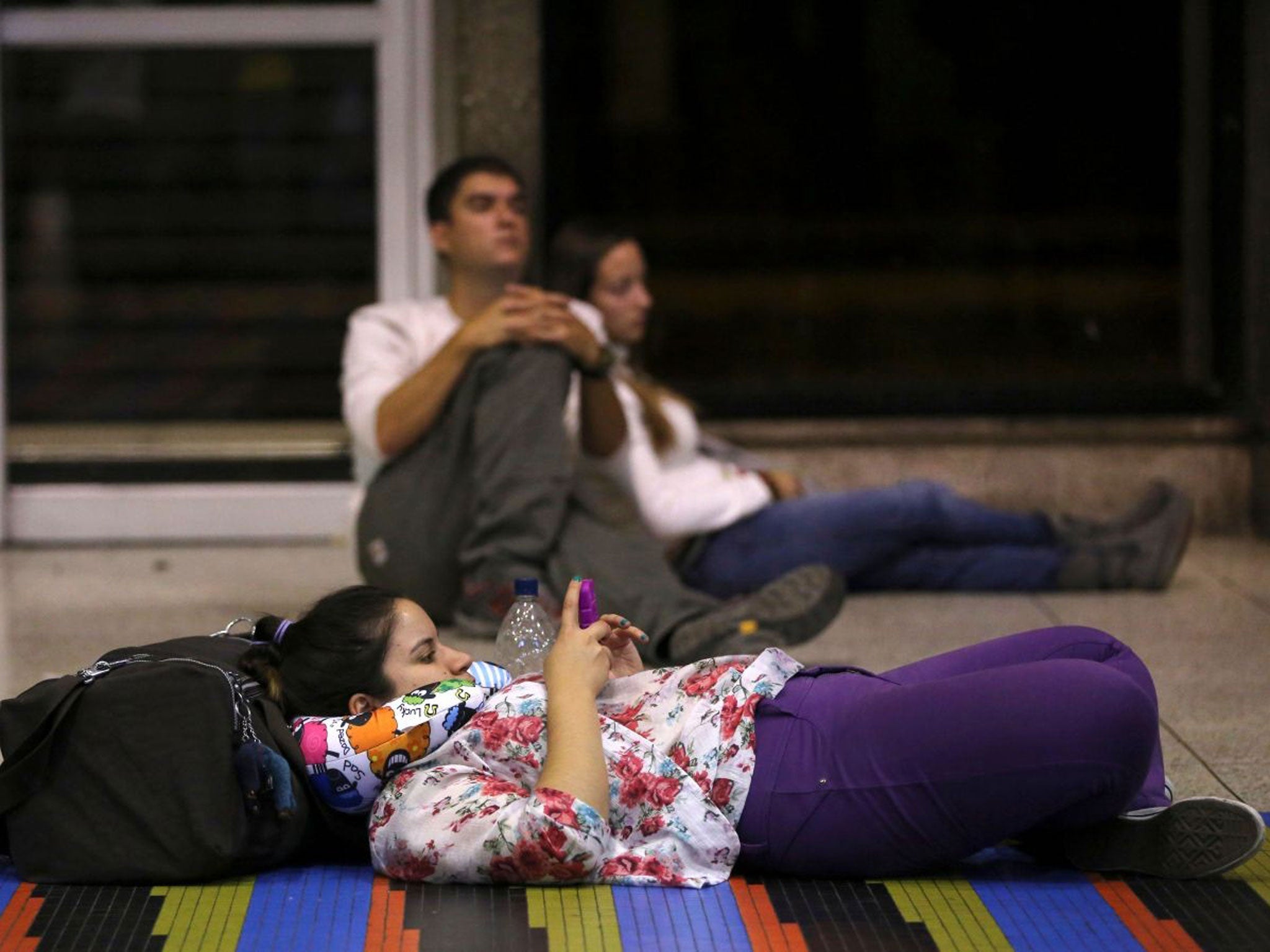 Passengers wait on the ground front of the Air France desk after their flight to Paris was canceled