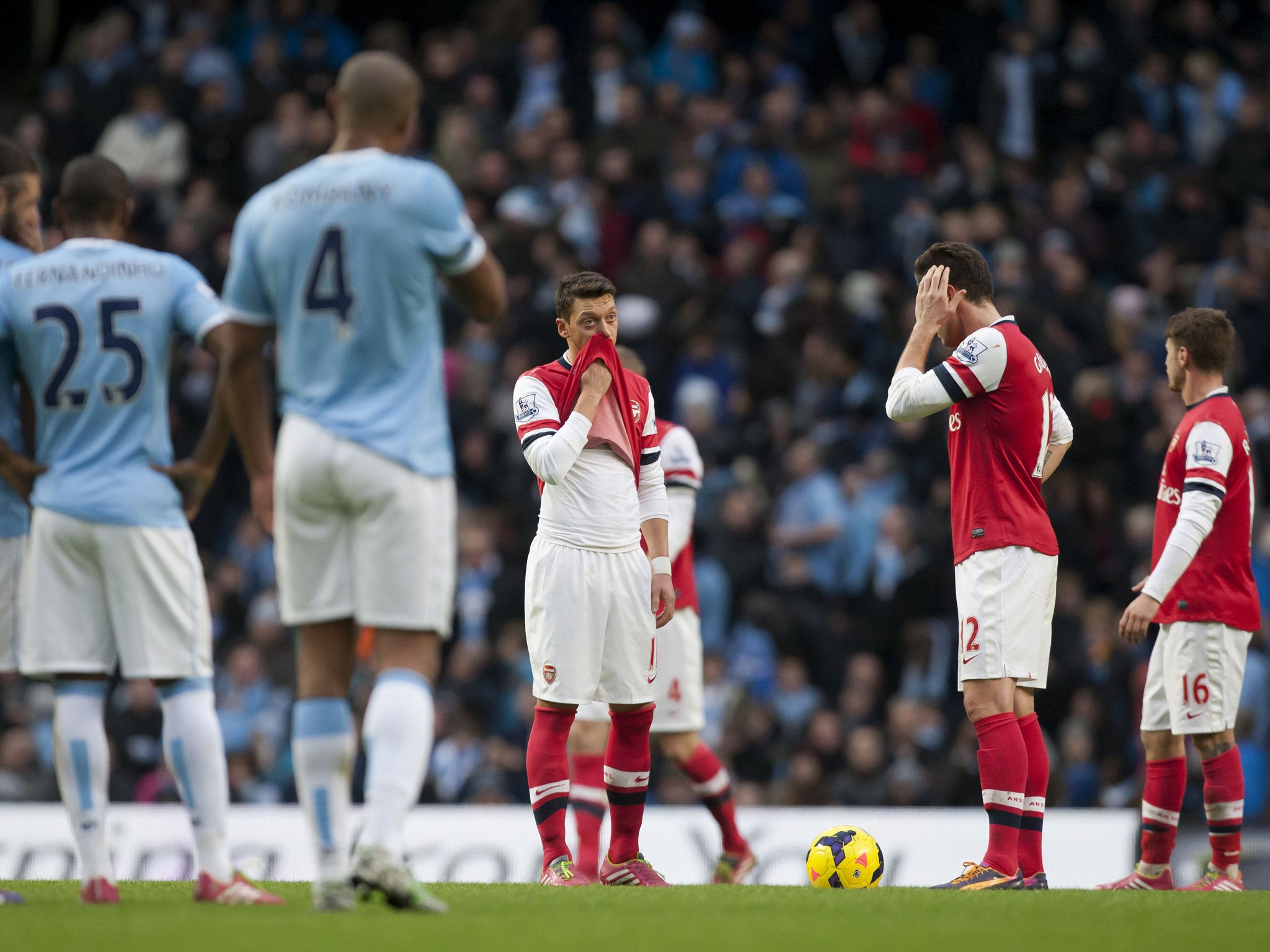 Arsenal's Mesut Özil (centre) looks downcast after Manchester City's fourth goal at the Etihad