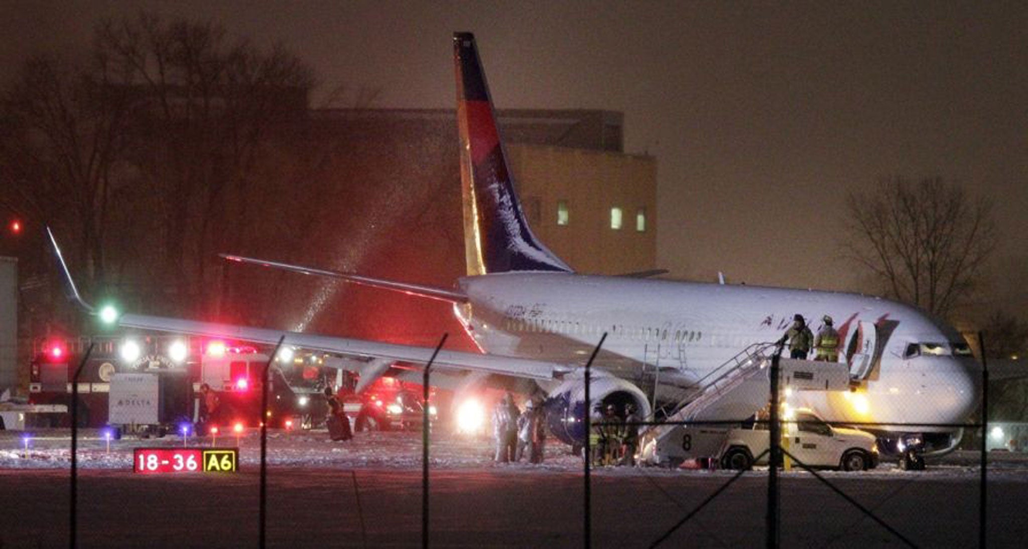 Authorities investigate the scene of a Delta Air Lines Boeing 737-800 jet that slid off a runway in the snow after arriving at Dane County Regional Airport in Madison, Wis