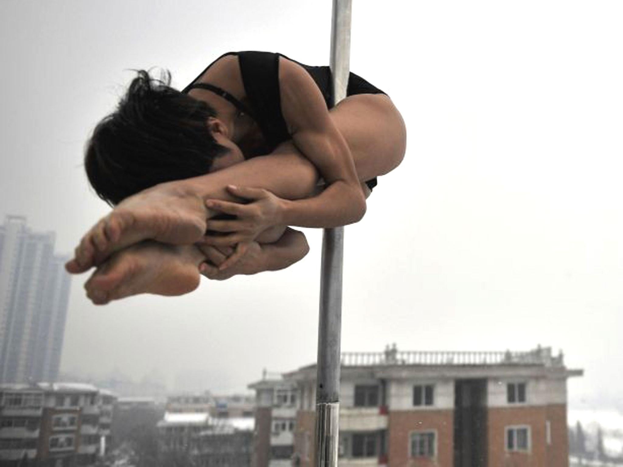 A pole dancer practices during a promotional event by members of China's national pole dancing team