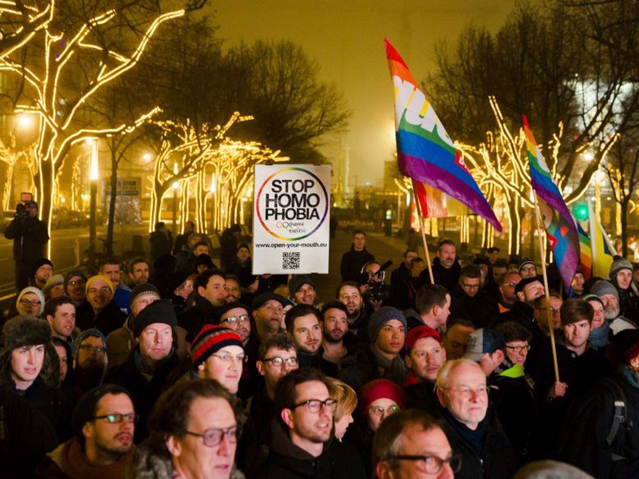 People hold a placard and rainbow flags as they call on the Russian authorities to lift anti-gay laws ahead of the Sochi 2014 Olympics during a protest