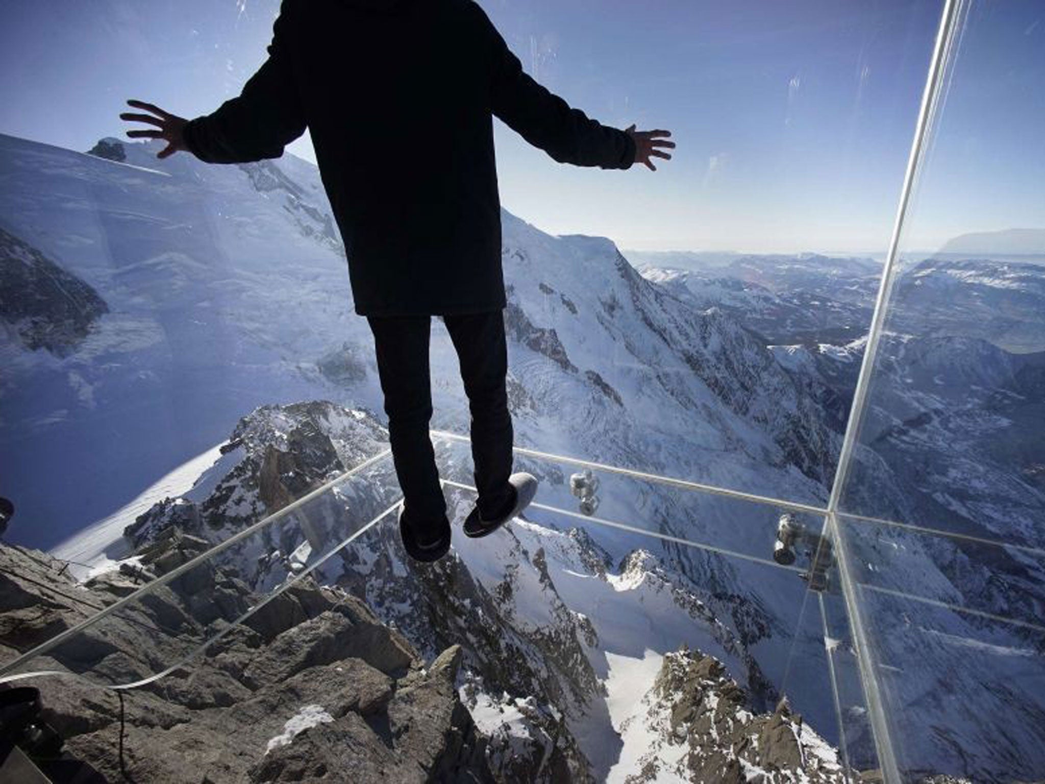 Don't look down - a man watches his balance as he steps onto the glass floor of the Chamonix Skywalk