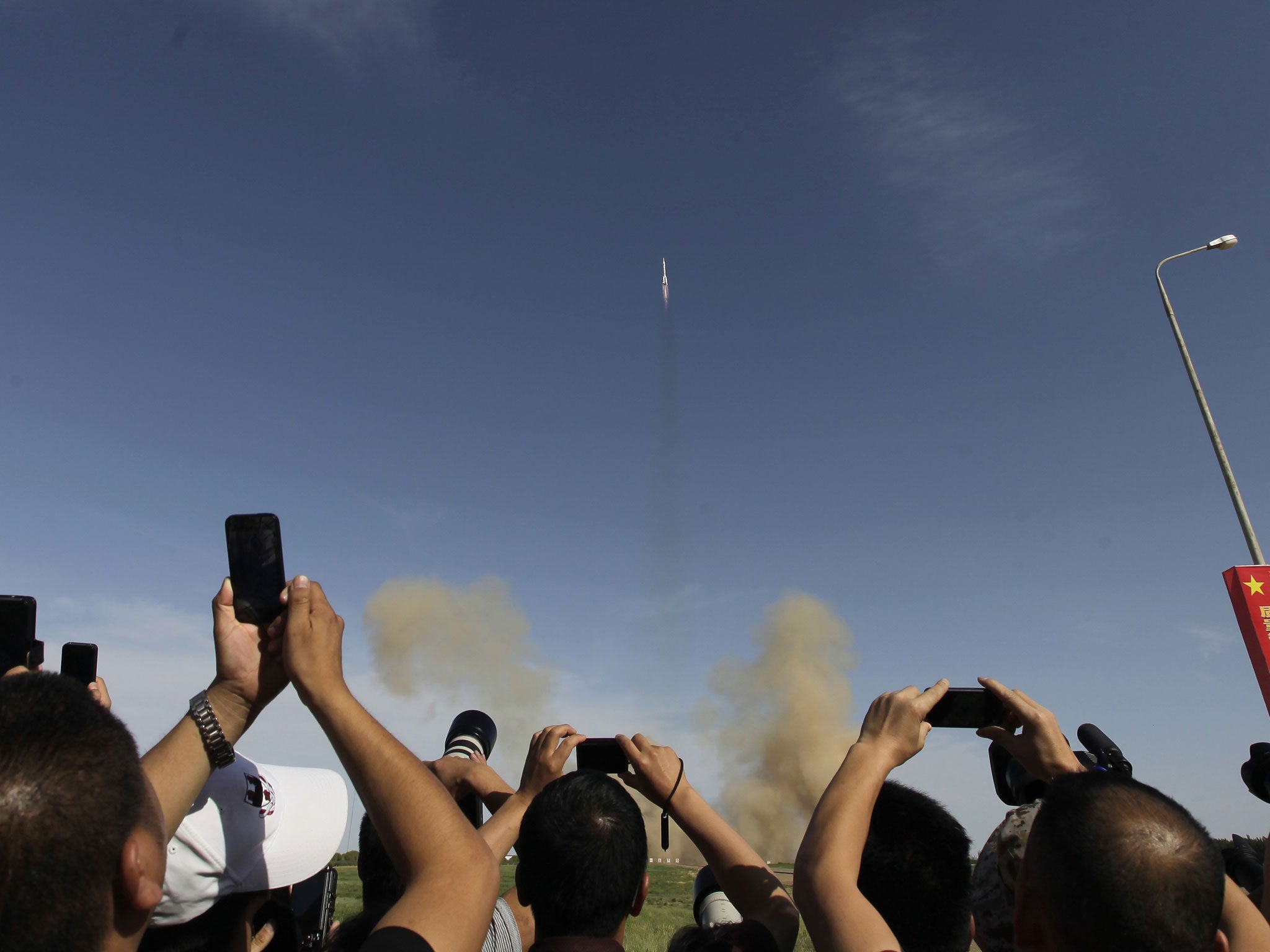 Chinese visitors take photos of the Changzheng-2F rocket with the Shenzhou-10 manned spacecraft carrying three Chinese astronauts