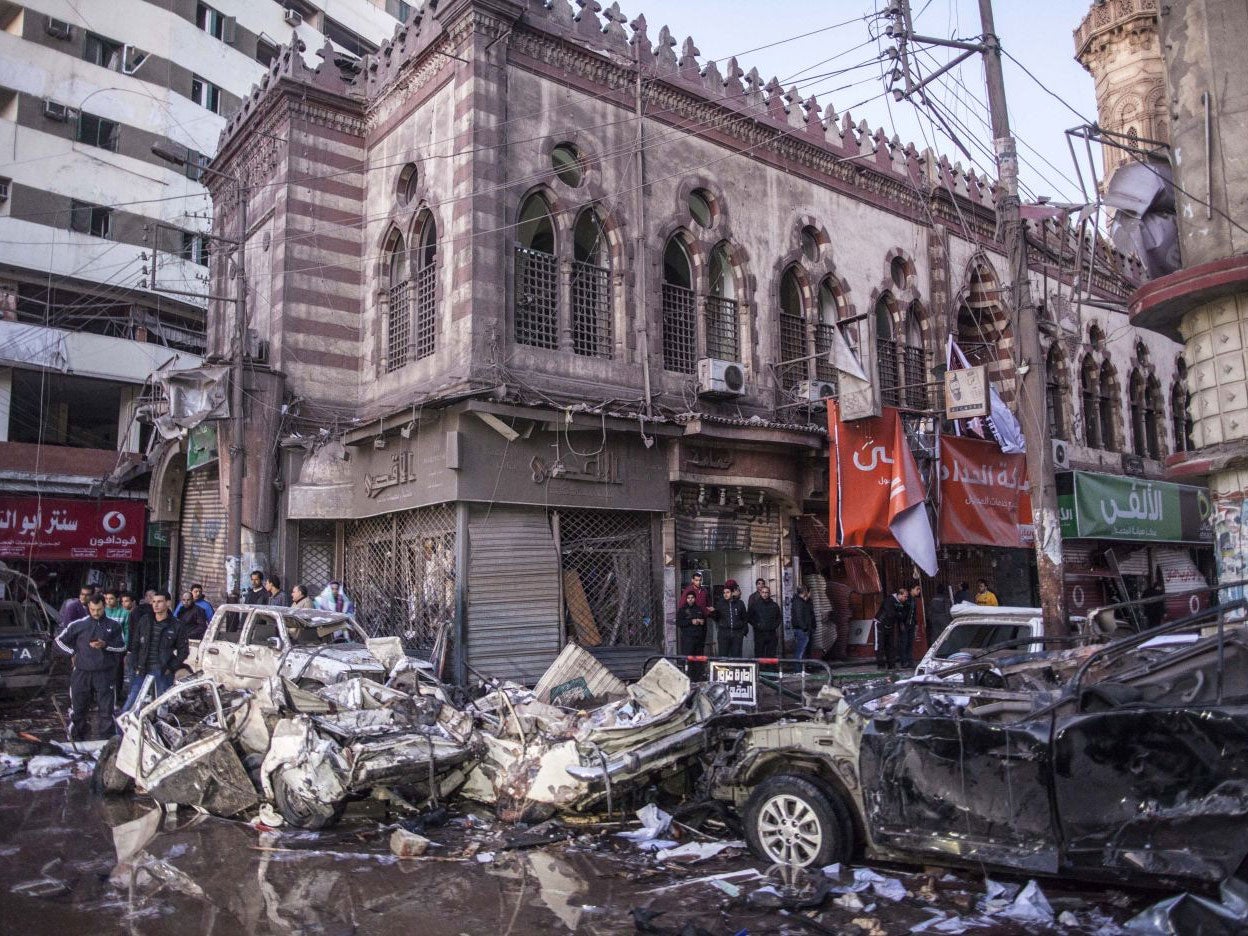 Men inspect the rubble in the Egyptian city of Mansoura, north of Cairo, following a powerful explosion