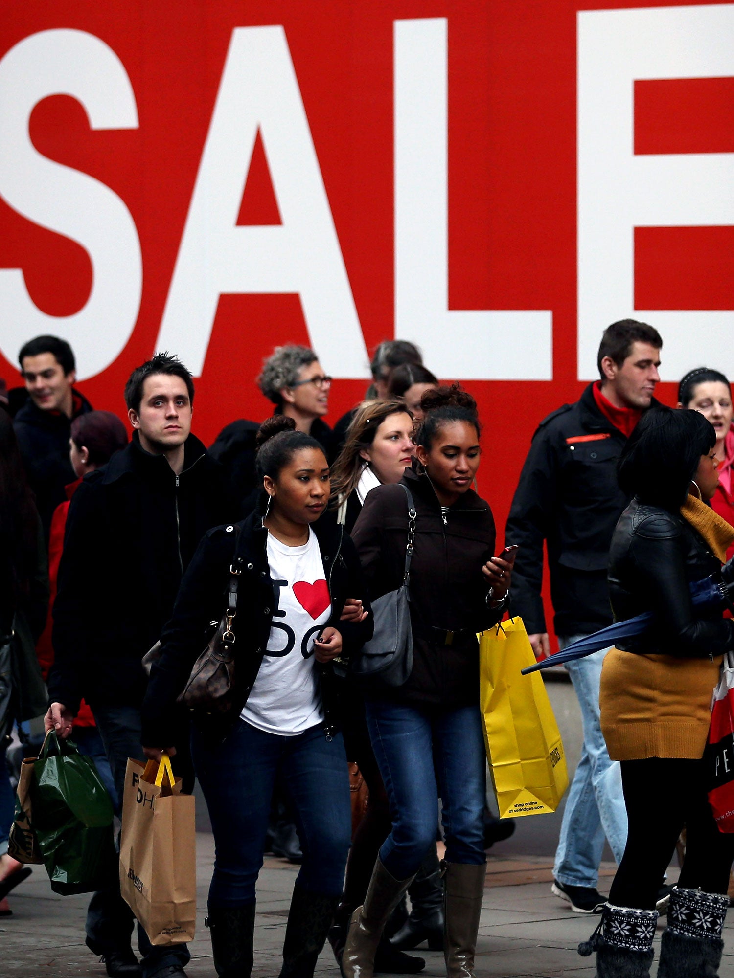 Shoppers pass sale signs as they make their way down Oxford Street.