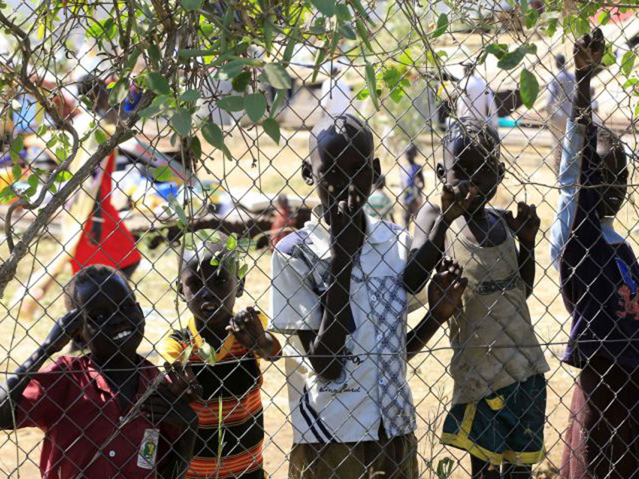 Children displaced by the fighting in South Sudan wait behind the fence of the United Nations Mission facility on the outskirts of the capital Juba. Tens of thousands of refugees have fled the crisis