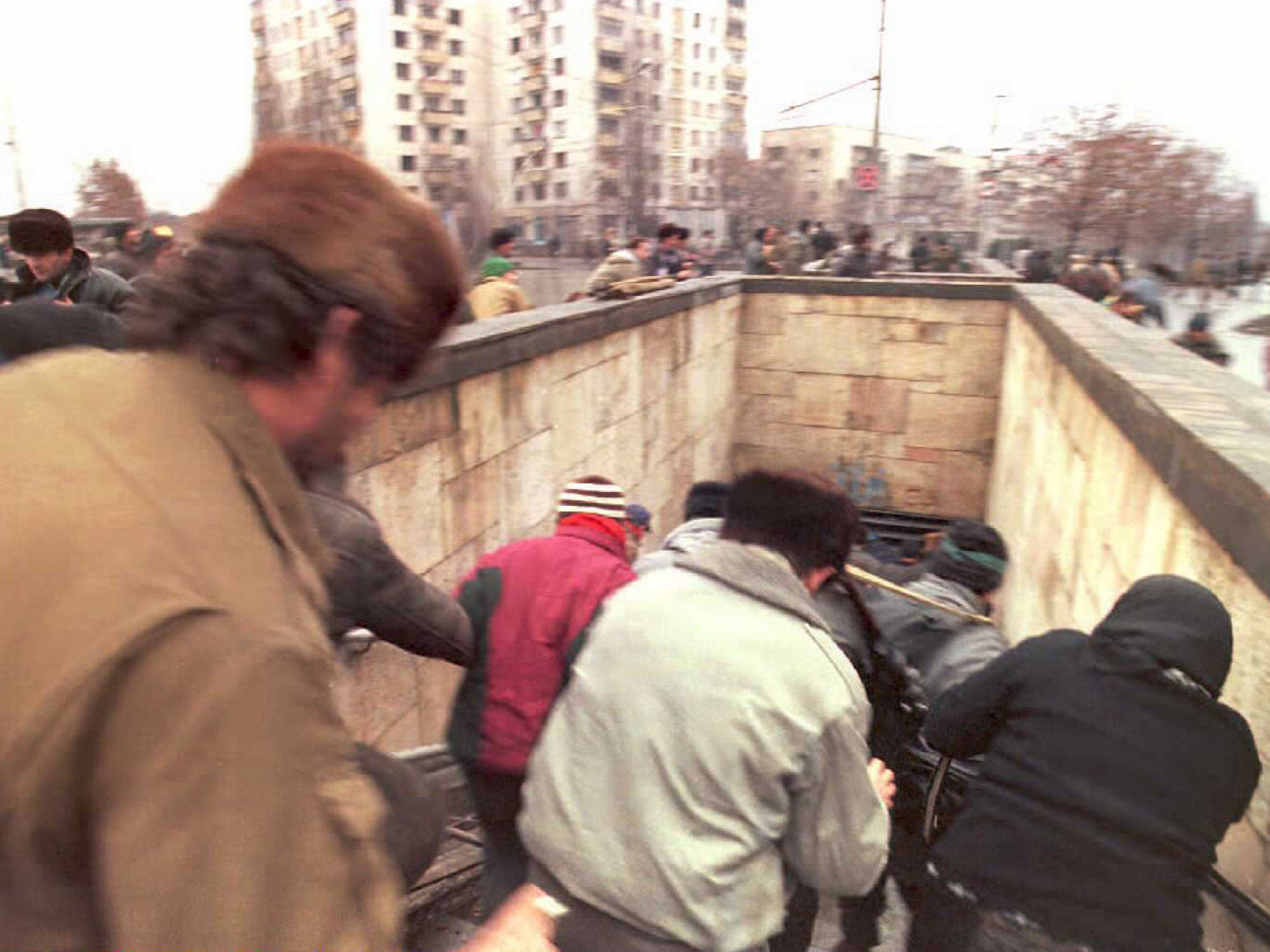 People run down the stairs of an underpass as Russian planes roar above them in downtown Grozny, Russia in 1994