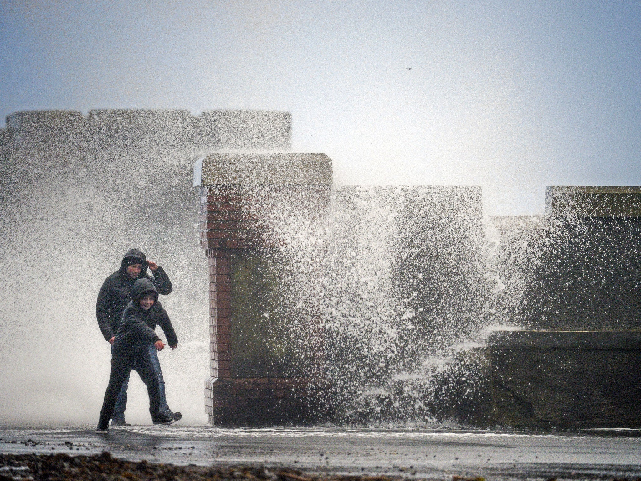 Martin and Sean McKinney dodge a wave at Saltcoats Harbour in Saltcoats, Scotland.