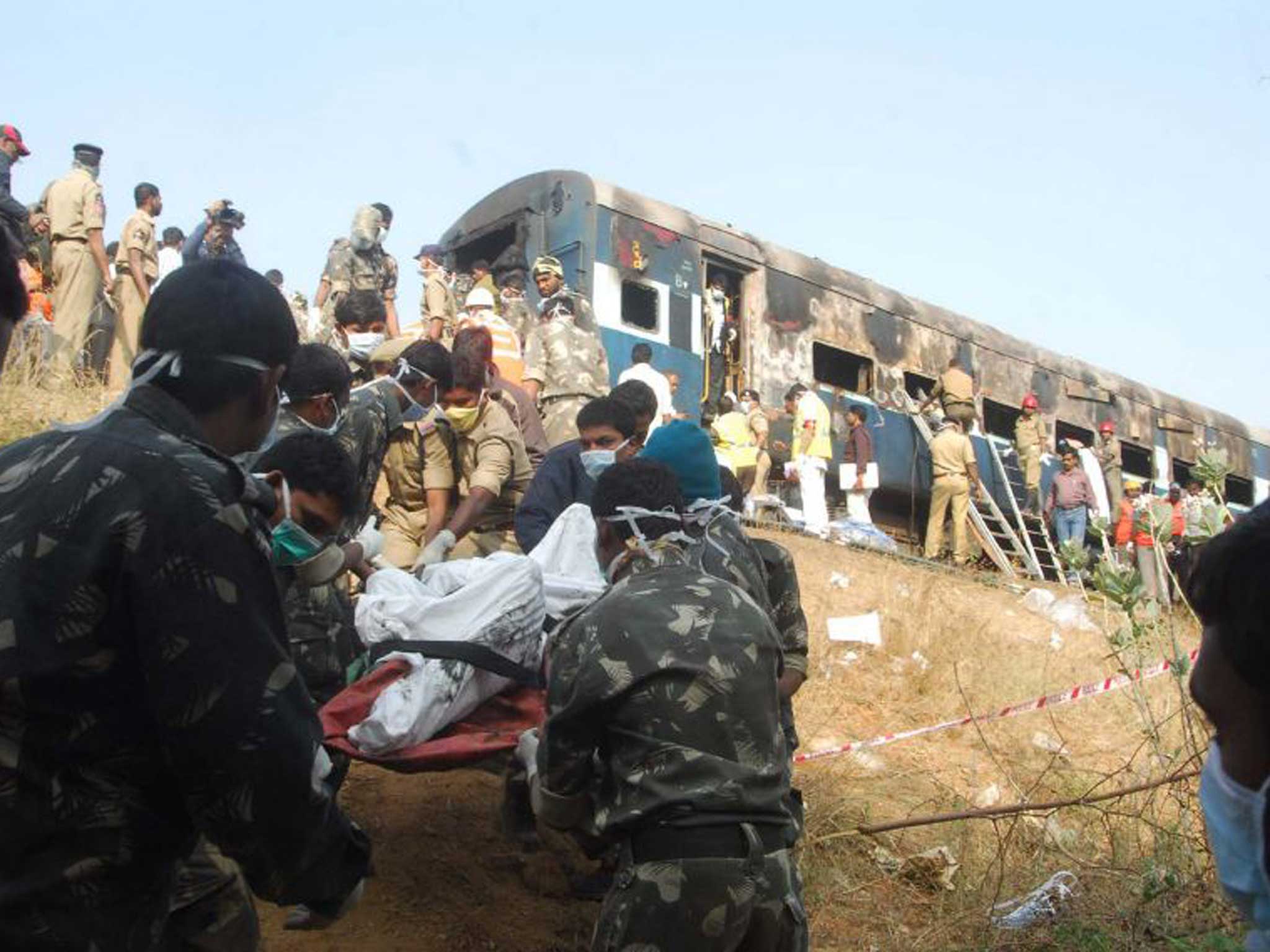 Indian rescue personnel use a stretcher to carry a body near a charred carriage of the Nanded-Bangalore Express. Authorities said most of those who died suffocated in the coaches that were filled with thick black smoke.