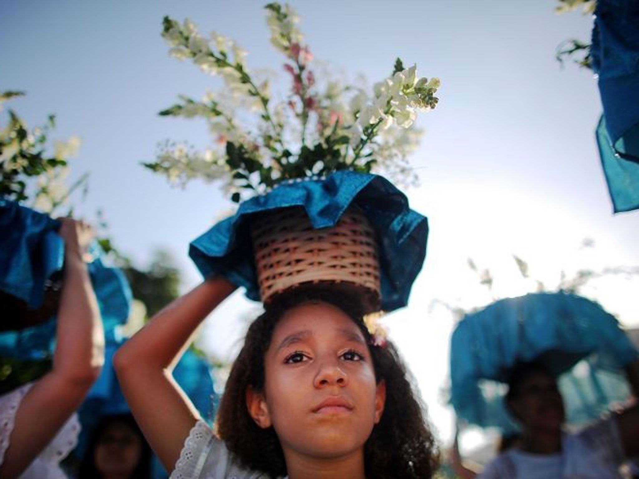 Women carry offerings at a ceremony honoring Iemanja, Goddess of the Sea, as part of traditional New Year's celebrations on the sands of Copacabana beach in Rio de Janeiro