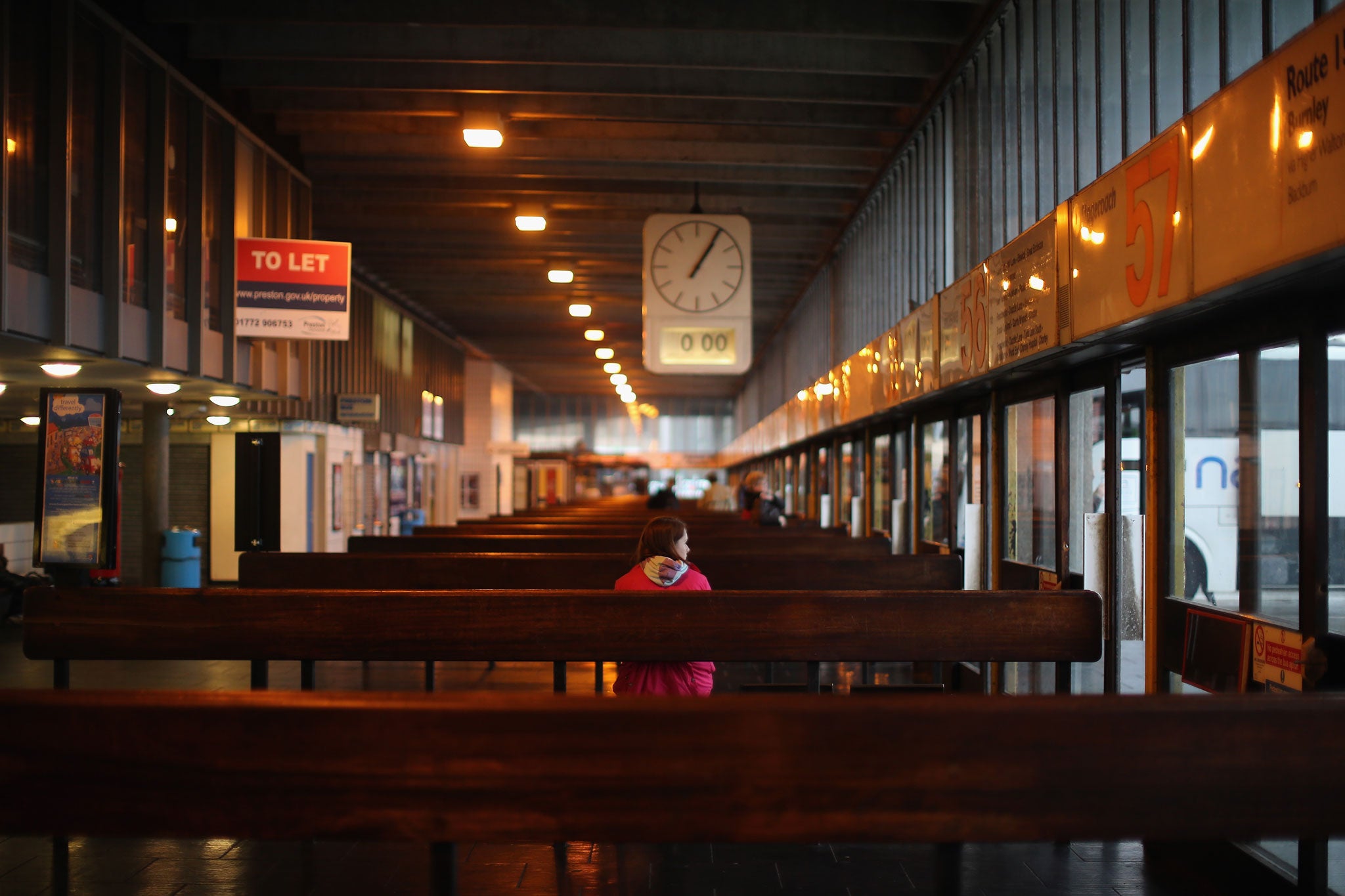 A traveller waits for a bus inside the listed station