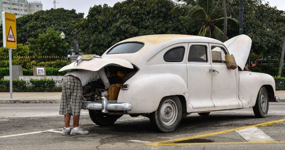 A Cuban attempts to repair his old car in Havana on the day the free sale of cars in Cuba was officially authorized.