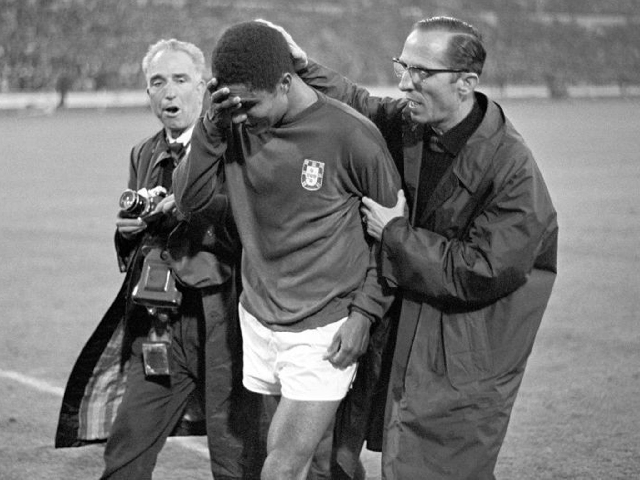 Portugal's Eusebio being consoled by a compatriot as he leaves the field in tears after Portugal had been defeated 1-2 by England in the 1966 World Cup semi-final at Wembley